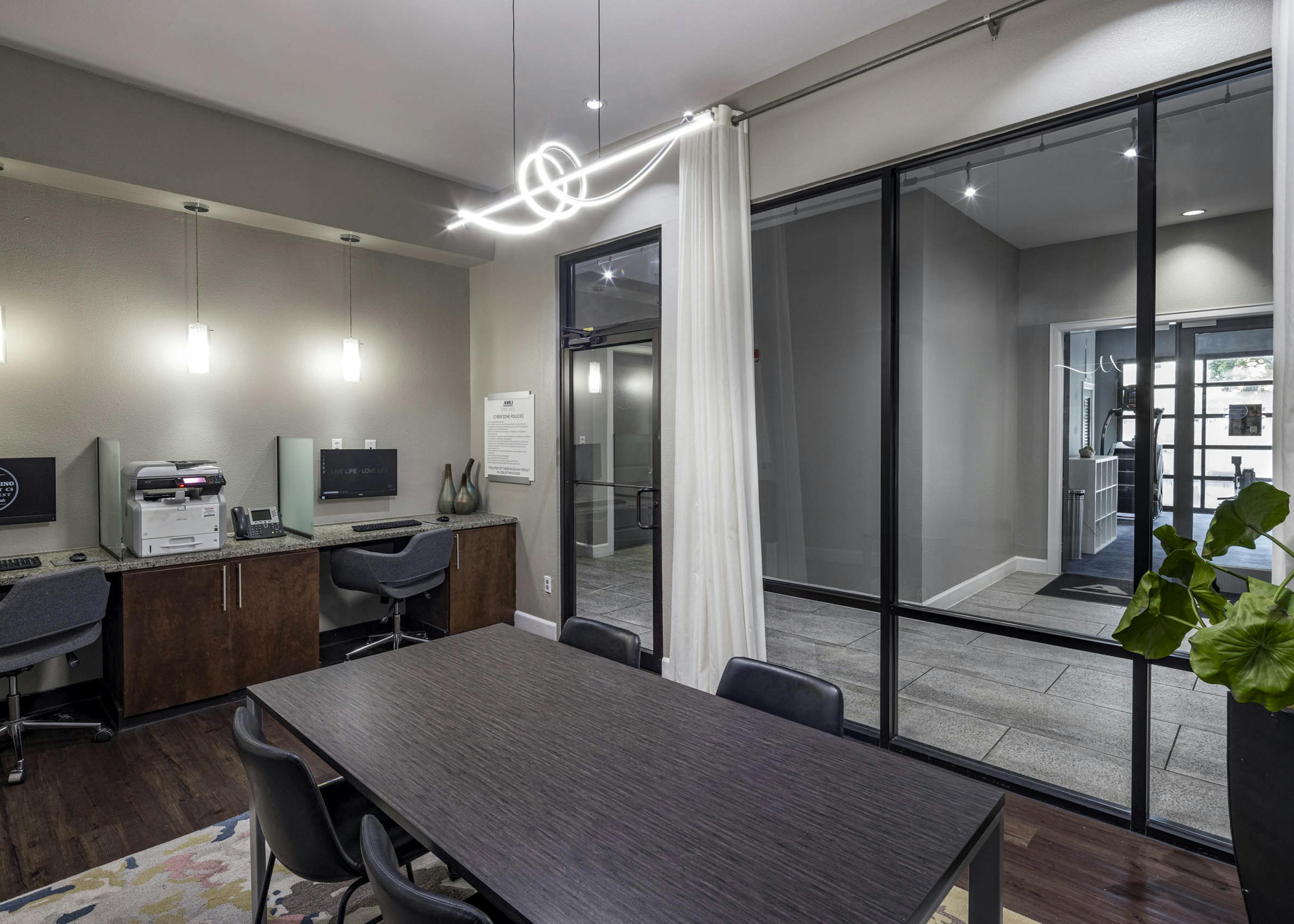 AMLI Eastside apartments business center with a conference table with four chairs, two computer workstations against a wall and a printer