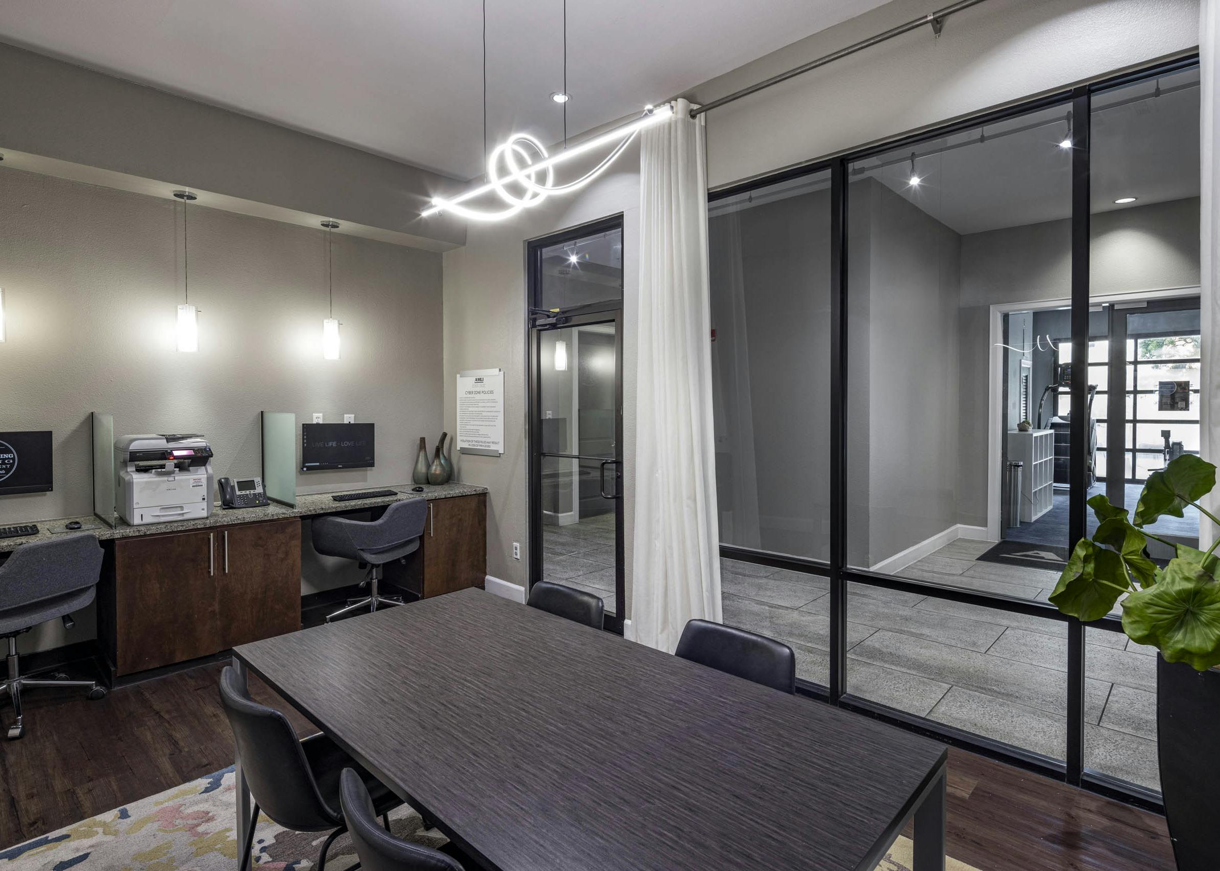 AMLI Eastside apartments business center with a conference table with four chairs, two computer workstations against a wall and a printer
