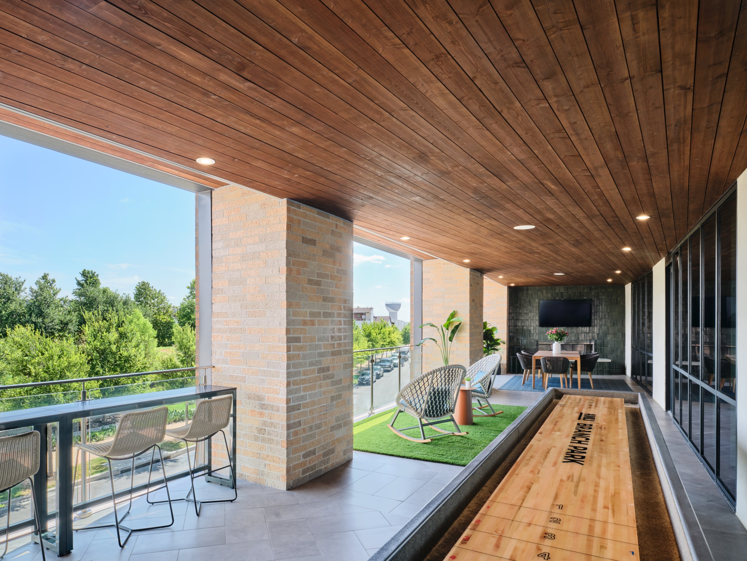 AMLI Branch Park apartments resident lounge outdoor area with a shuffleboard area and lounge seating areas overlooking the park