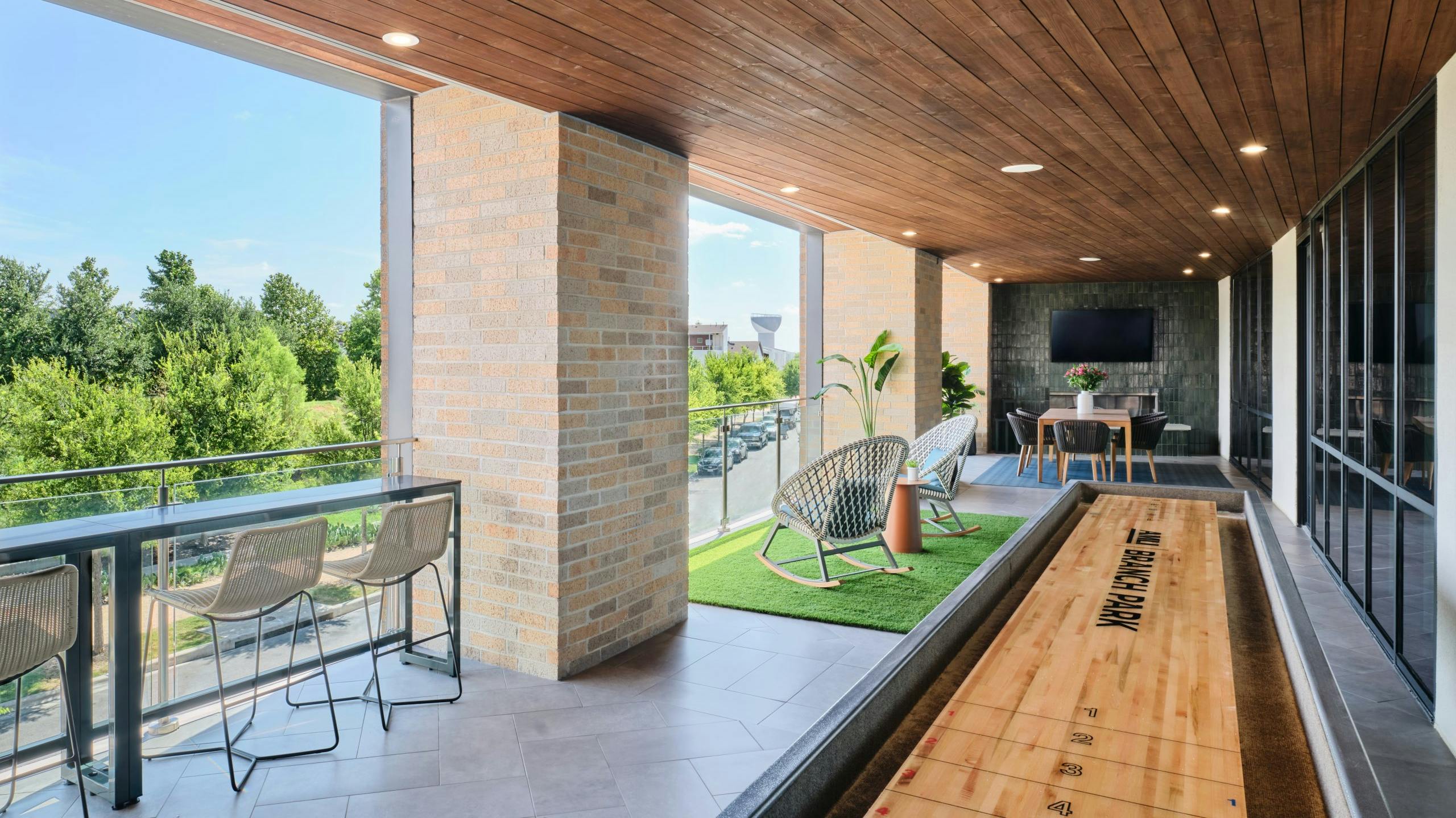 AMLI Branch Park apartments resident lounge outdoor area with a shuffleboard area and lounge seating areas overlooking the park