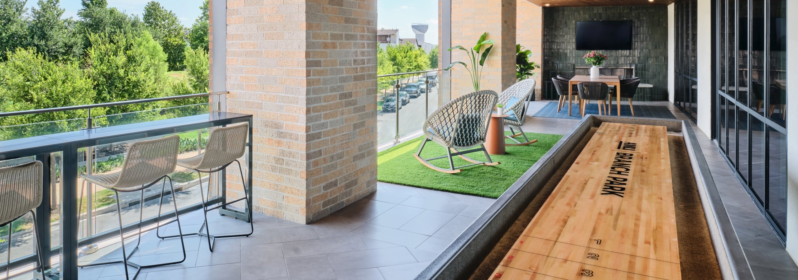 AMLI Branch Park apartments resident lounge outdoor area with a shuffleboard area and lounge seating areas overlooking the park
