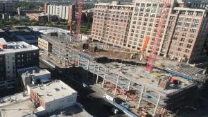 AMLI Golden Triangle apartment building under construction with a few floors built and tall orange cranes on top
