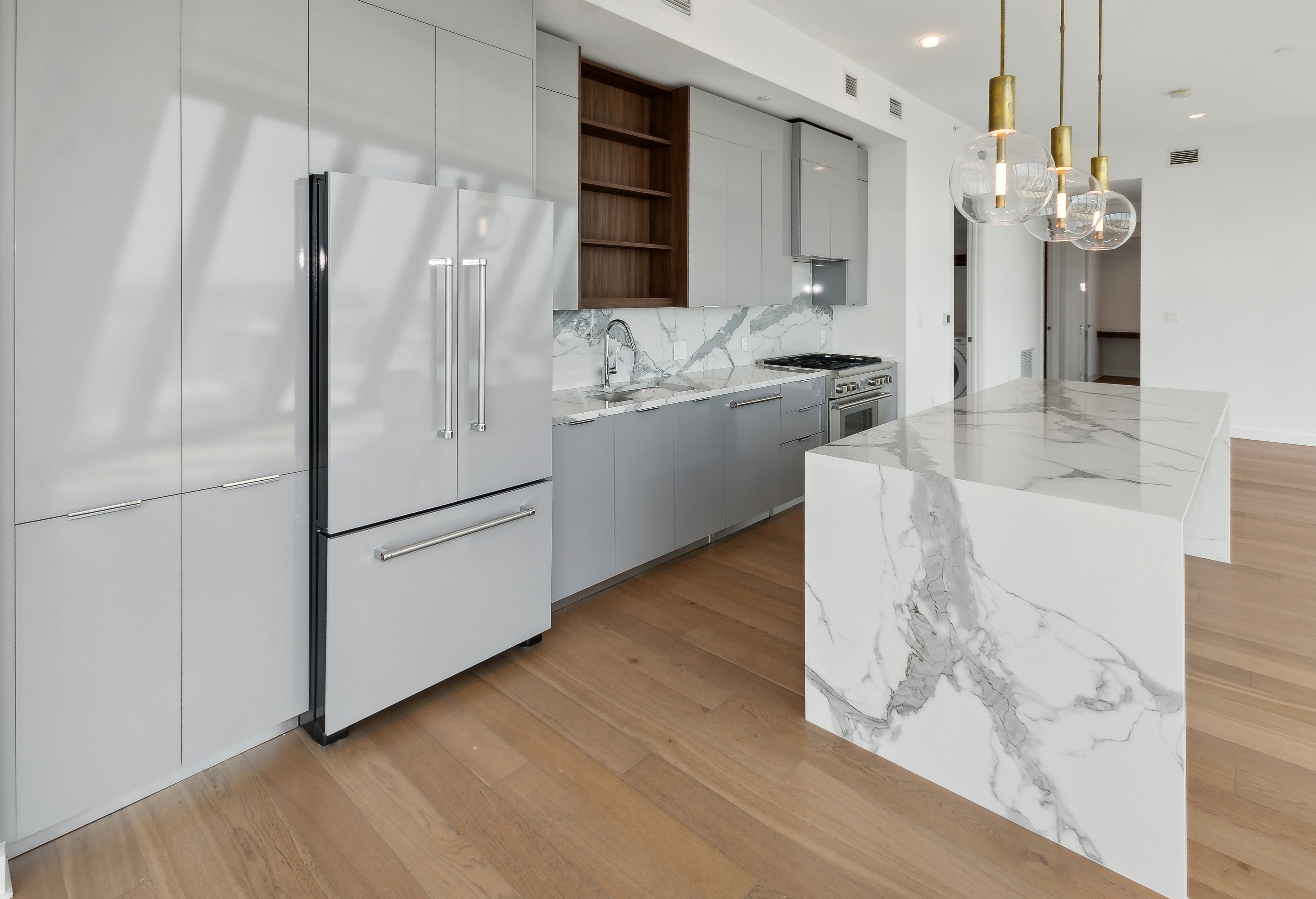 AMLI Fountain Place penthouse apartment kitchen with gray cabinetry with gray paneled refrigerator and gray and white waterfall island