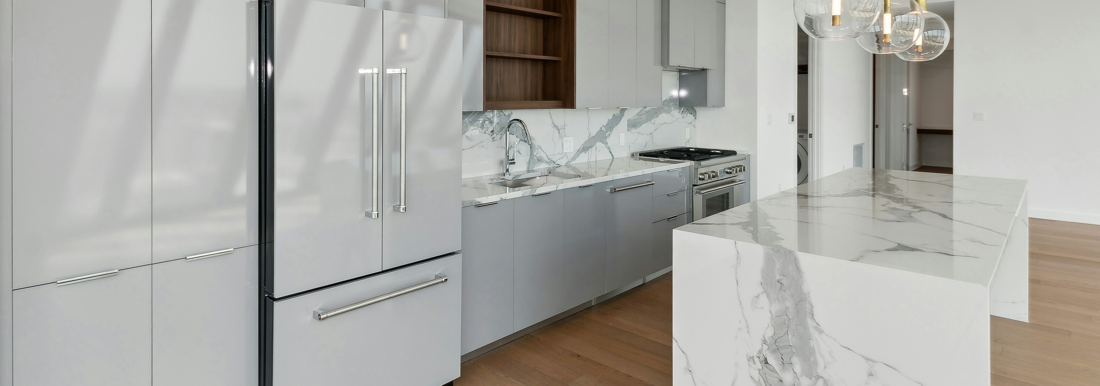 AMLI Fountain Place penthouse apartment kitchen with gray cabinetry with gray paneled refrigerator and gray and white waterfall island