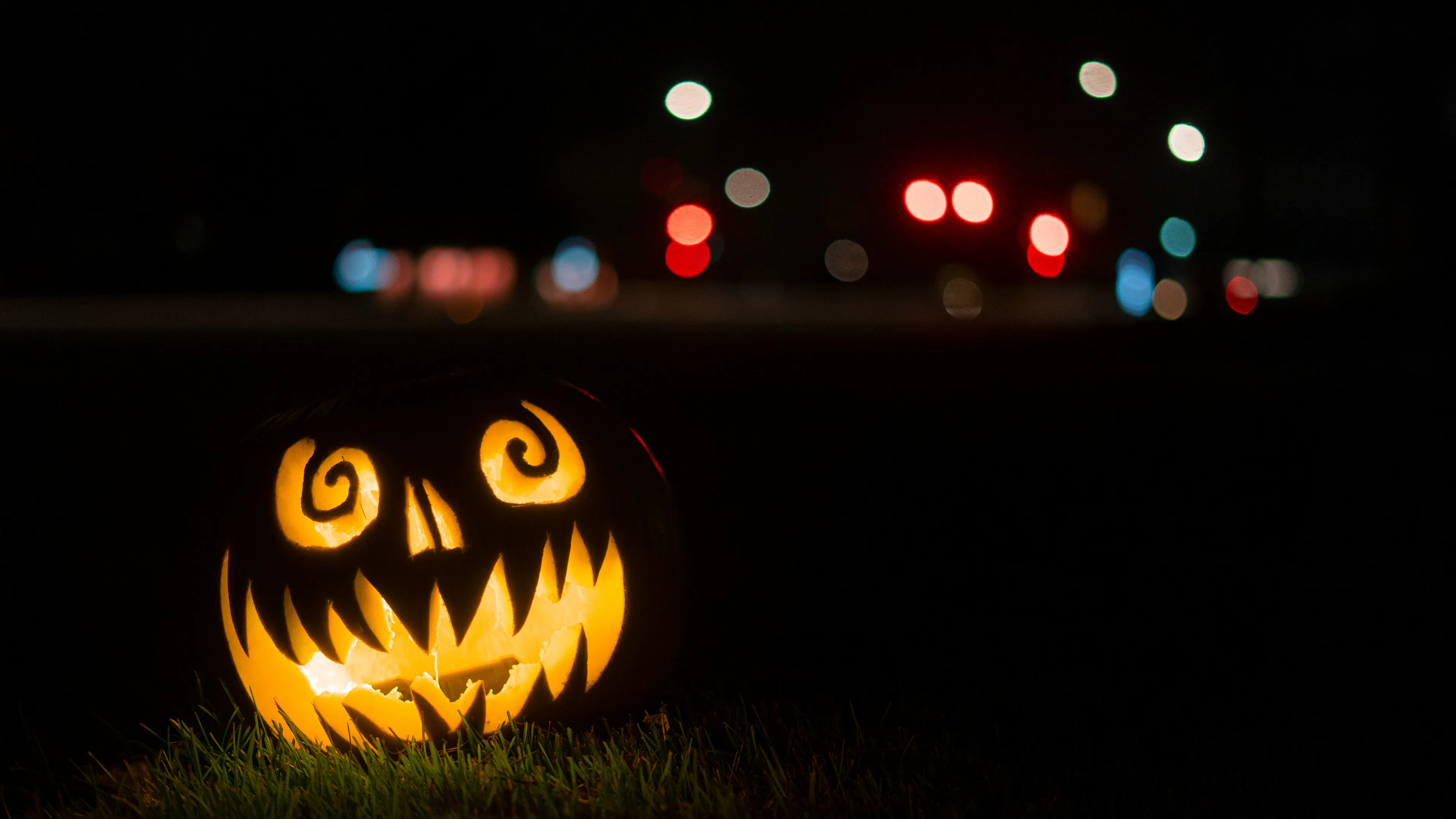 A jack-o-lantern with a funny face carved into it lit up with a candle shining in the dark