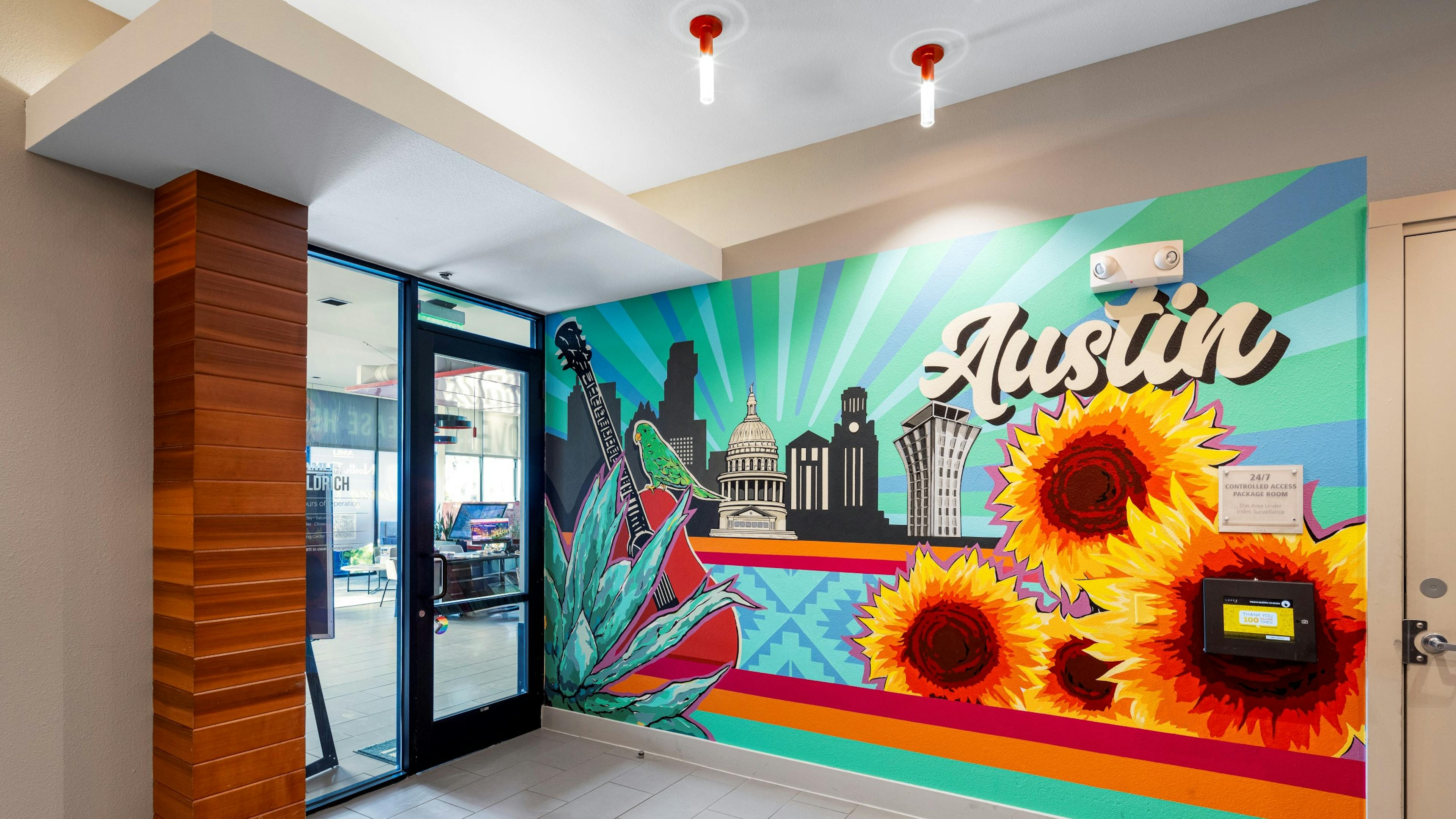 A colorful mural in the AMLI on Aldrich office with iconic Austin landmarks, large sunflowers, and the word "Austin" in bold script.