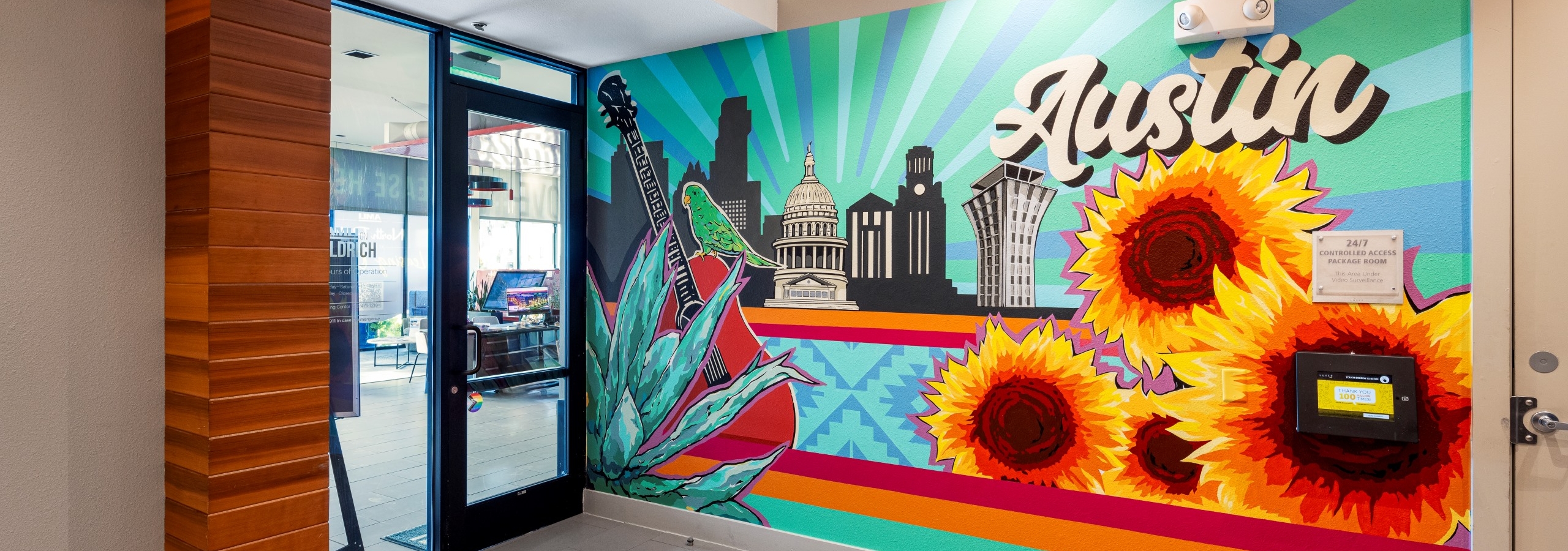 A colorful mural in the AMLI on Aldrich office with iconic Austin landmarks, large sunflowers, and the word "Austin" in bold script.