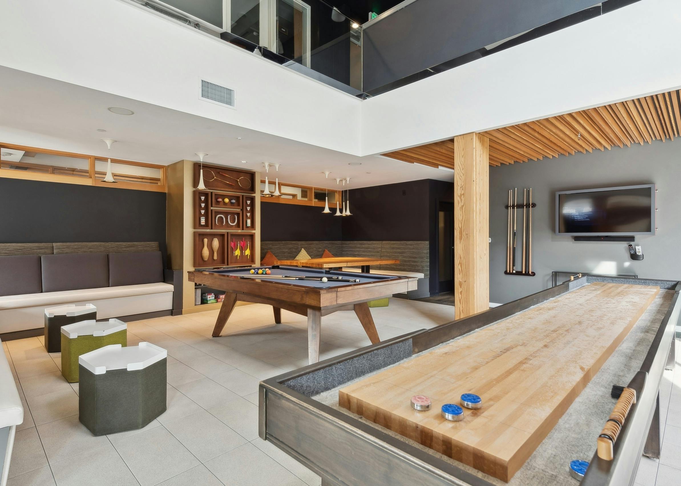 Resident game room at AMLI Wallingford apartments with a billiards table and shuffleboard with a board game shelf in the background.