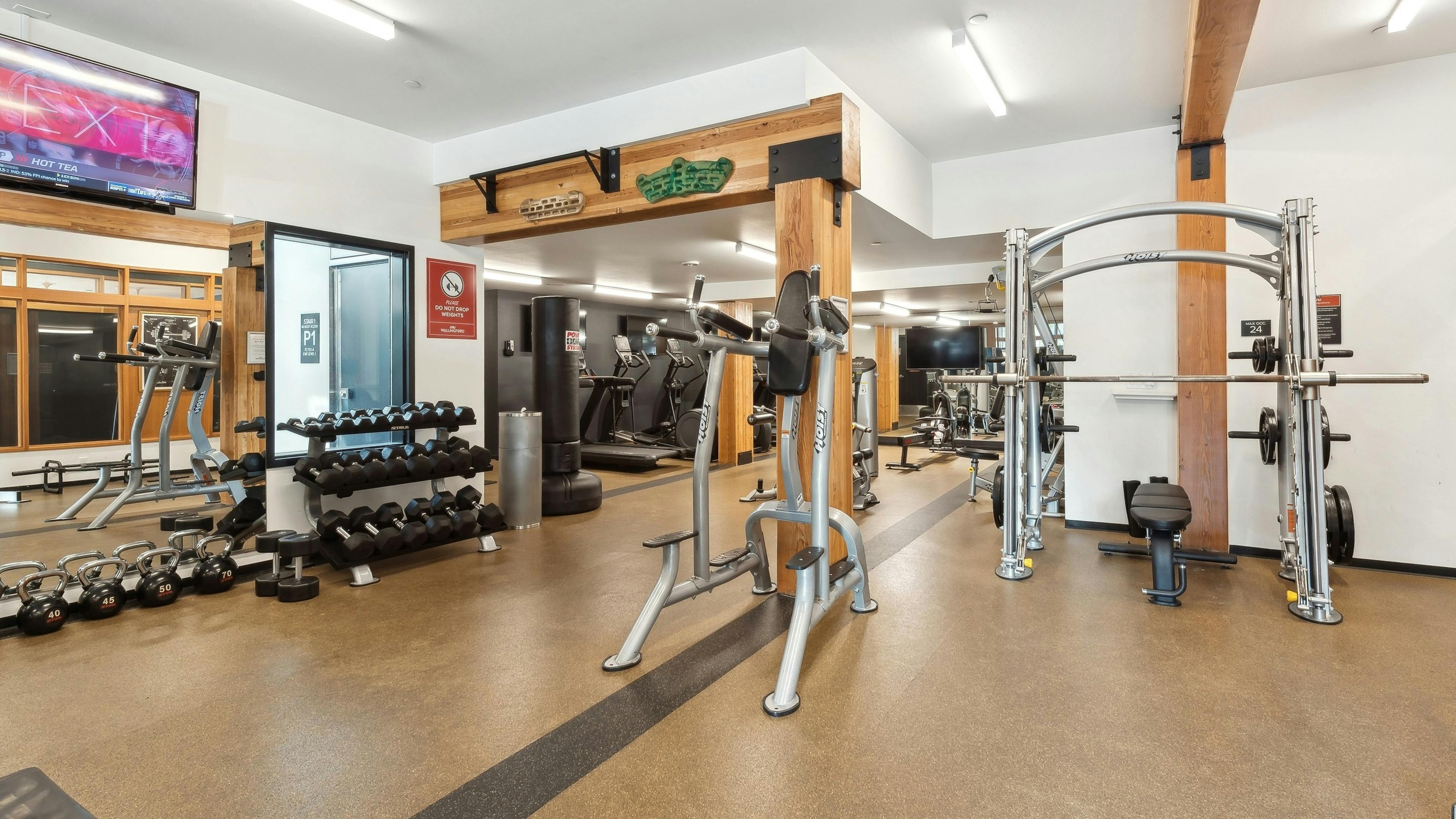 Multiple free weight and cardio machines at AMLI Wallingford fitness center including elliptical machines and a dumbbell rack.