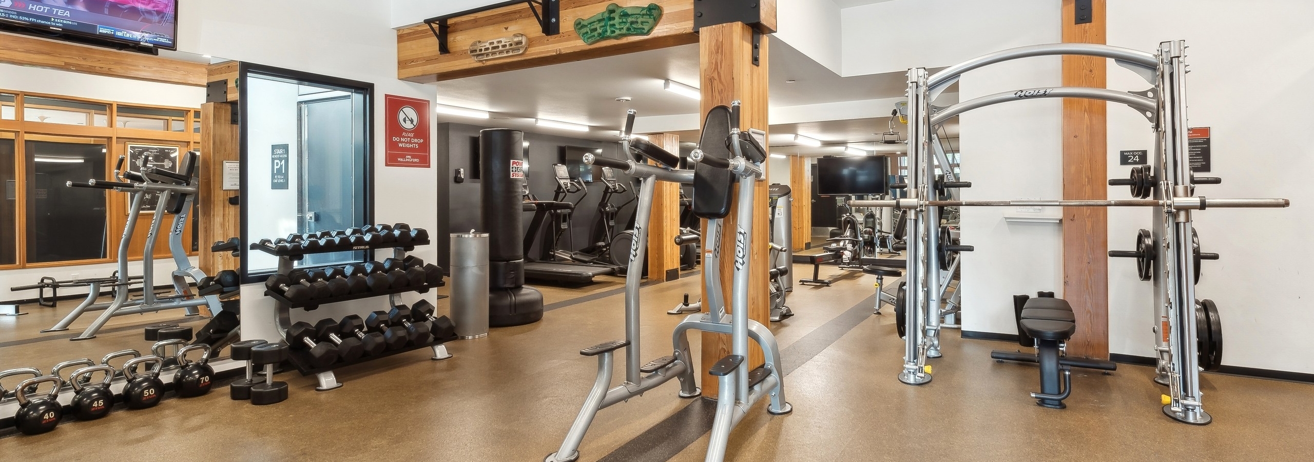 Multiple free weight and cardio machines at AMLI Wallingford fitness center including elliptical machines and a dumbbell rack.