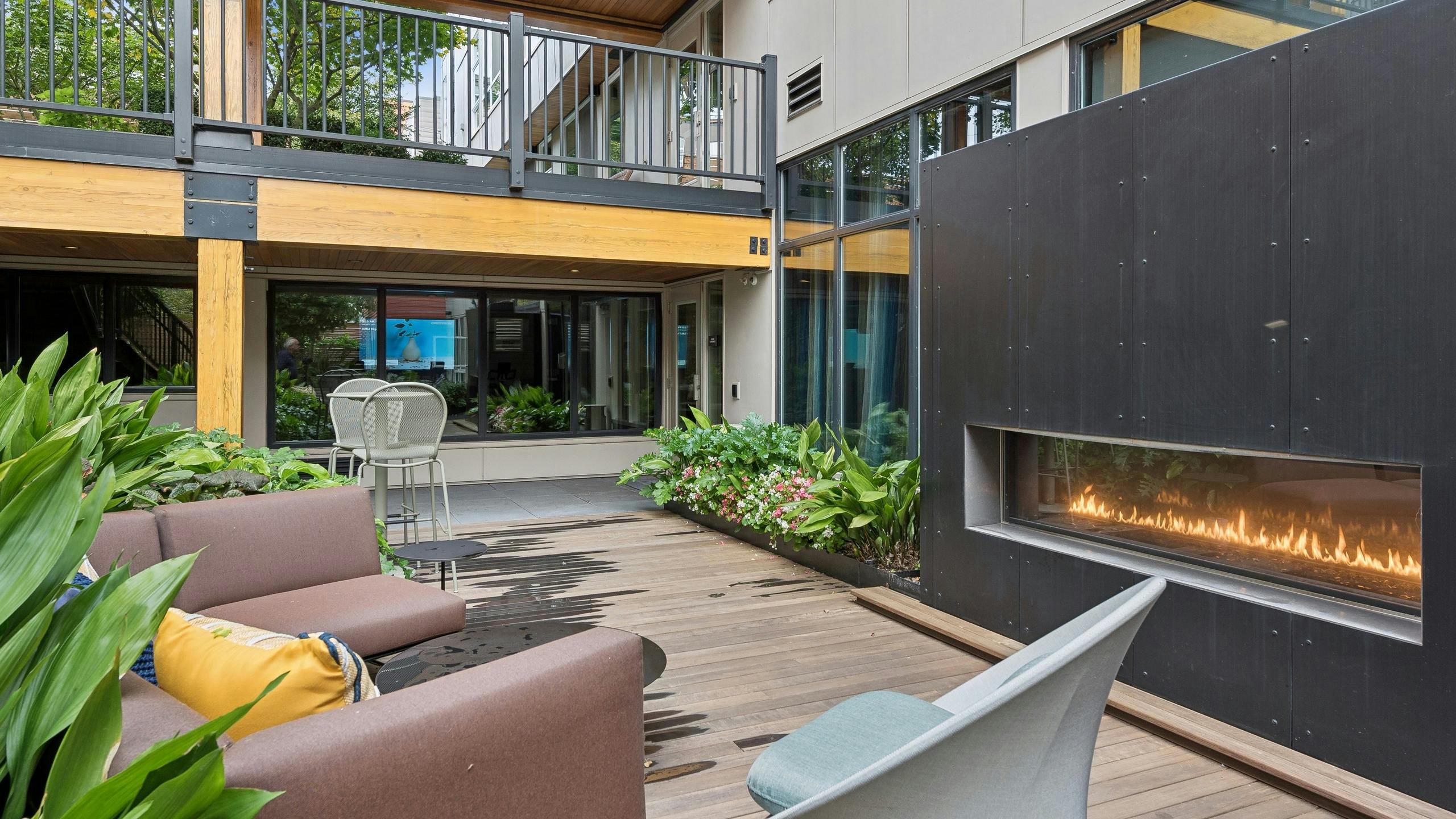 Resident courtyard ay AMLI Wallingford apartments with an outdoor fireplace and lots of green landscaping surrounding lounge furniture