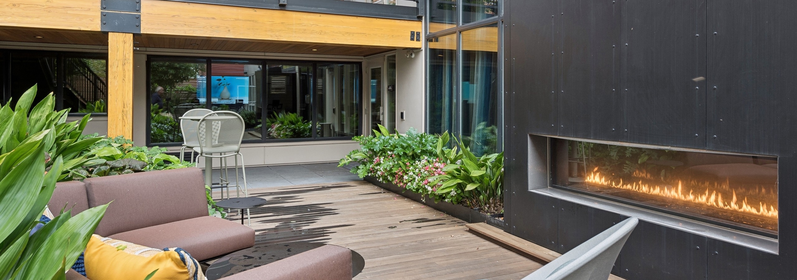 Resident courtyard ay AMLI Wallingford apartments with an outdoor fireplace and lots of green landscaping surrounding lounge furniture