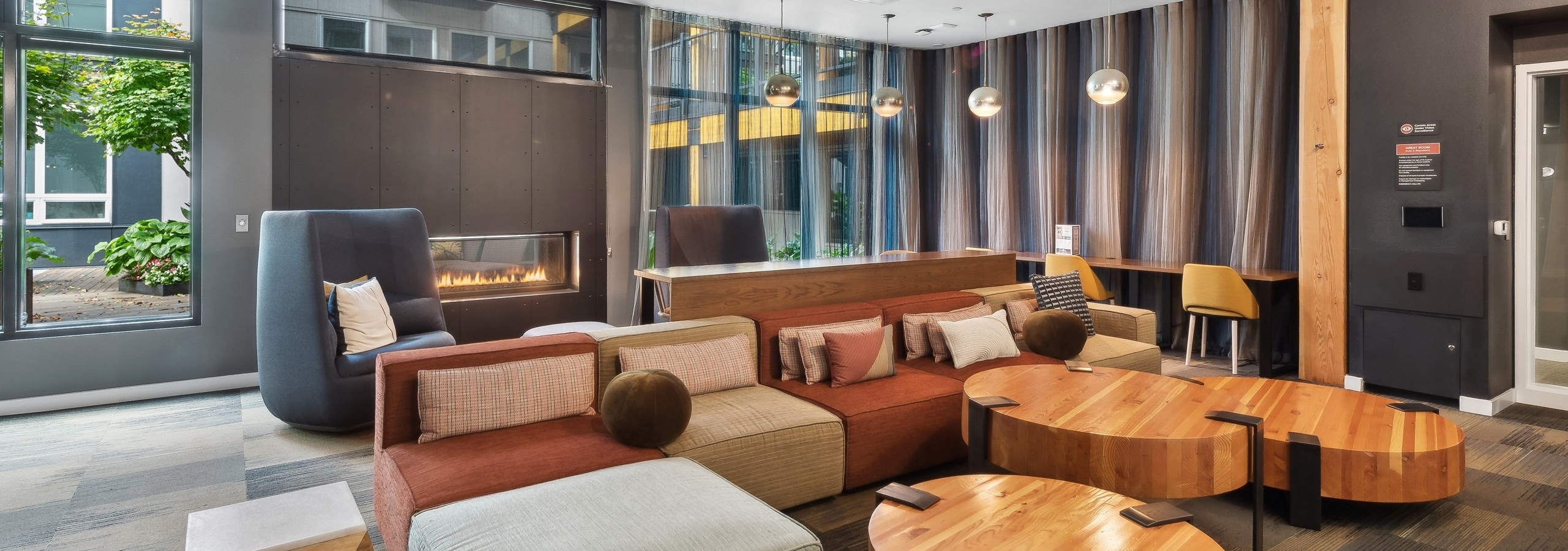 AMLI Wallingford resident lounge with an oversized couch with multiple pillows and a fireplace in the background with a roaring fire.