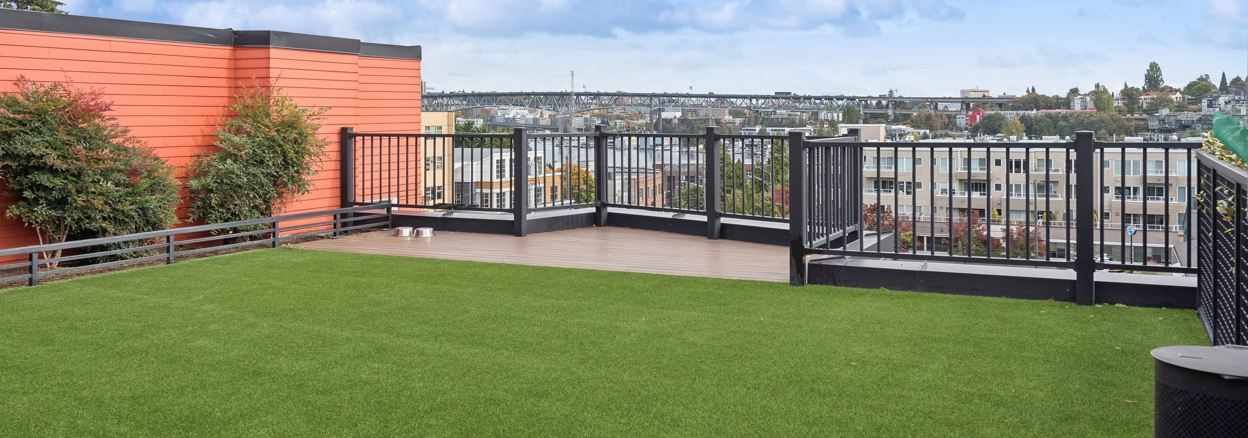 Pet relief area with green turf on AMLI Wallingford apartments rooftop showcasing views of Seattle skyline and Lake Union.