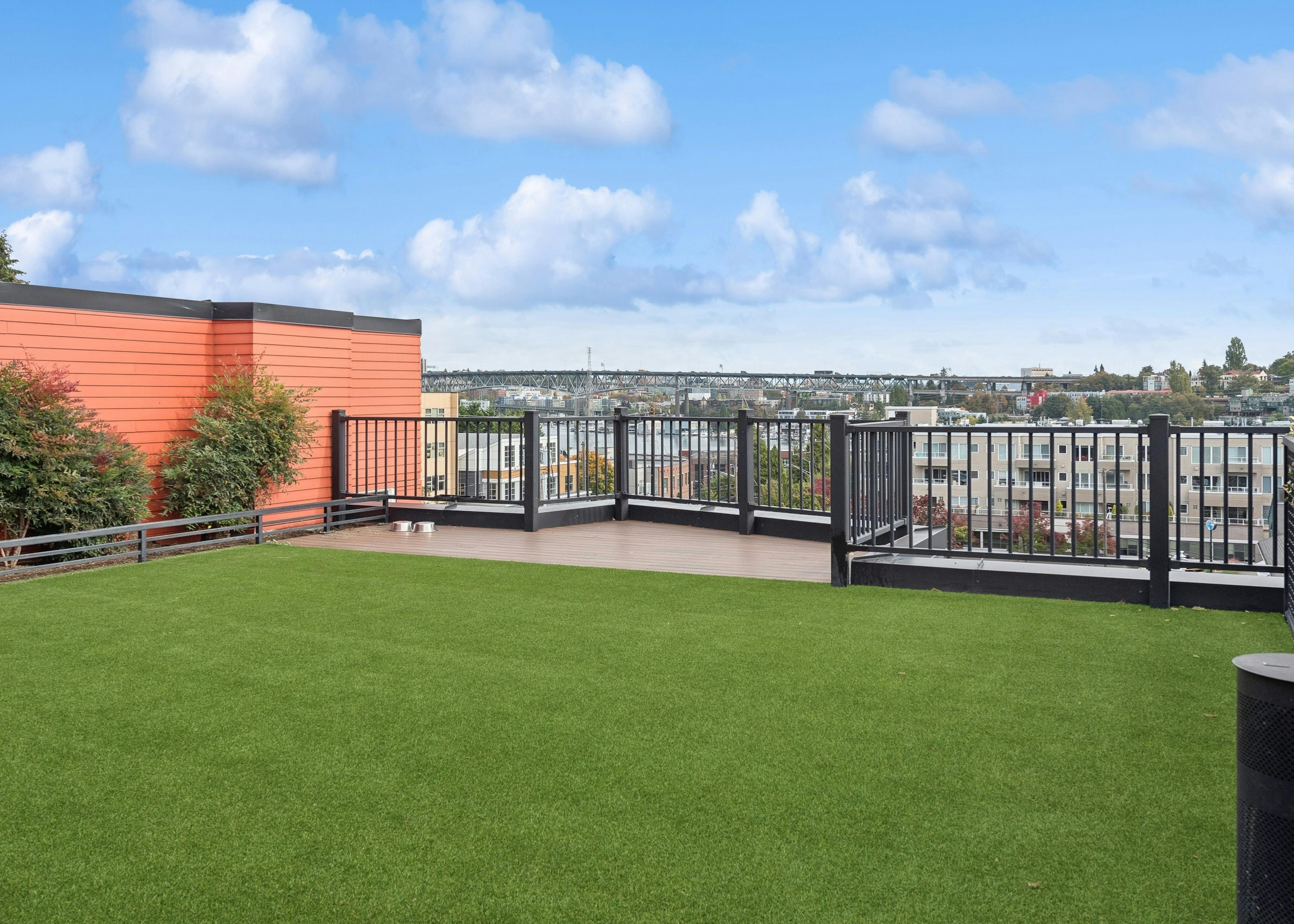 Pet relief area with green turf on AMLI Wallingford apartments rooftop showcasing views of Seattle skyline and Lake Union.
