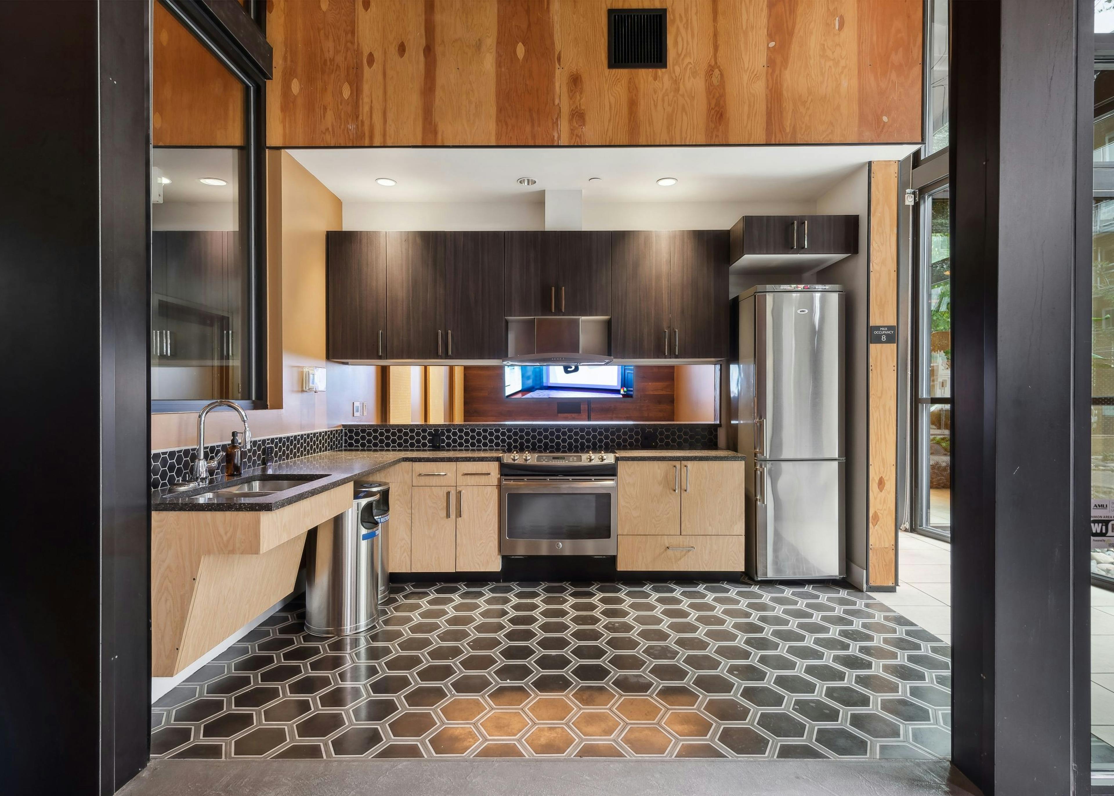 Resident kitchen at AMLI South Lake Union featuring wooden cabinets with tile backsplash and stainless steel appliances