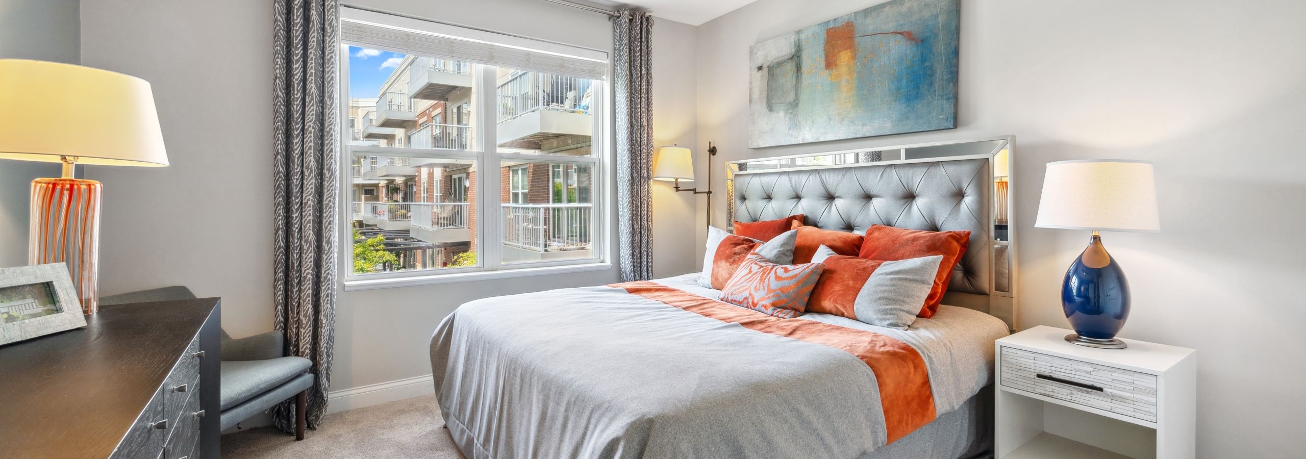 AMLI Deerfield bedroom with window and king size bed with night stands across from dresser with a chair in a corner and lamps