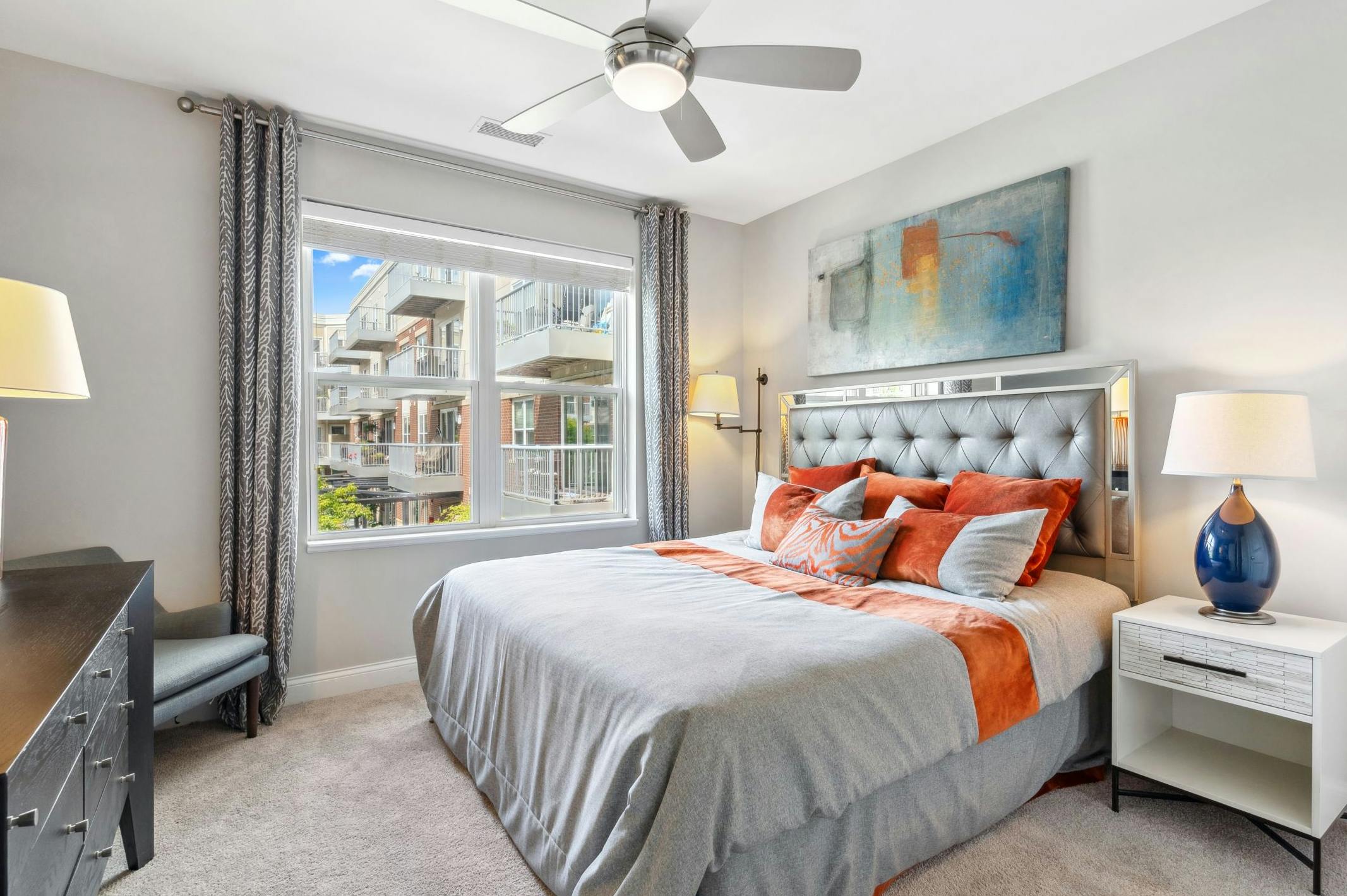 AMLI Deerfield bedroom with window and king size bed with night stands across from dresser with a chair in a corner and lamps