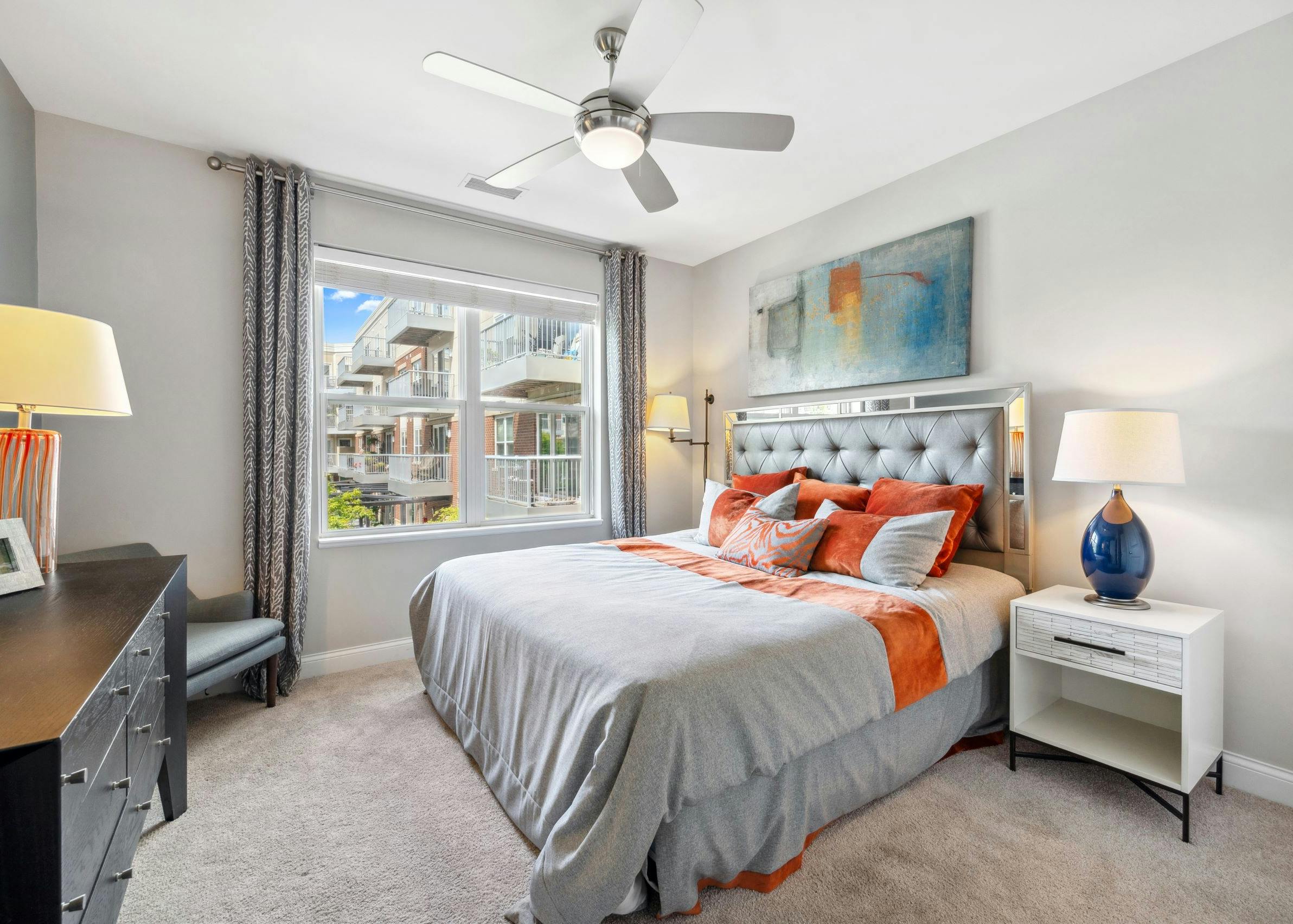 AMLI Deerfield bedroom with window and king size bed with night stands across from dresser with a chair in a corner and lamps