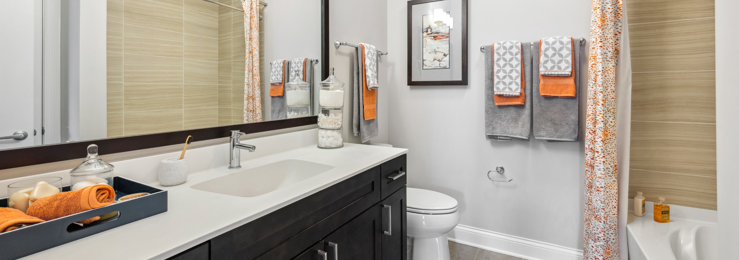 Interior view of an AMLI Deerfield bathroom with large mirror, dark wood cabinets, white countertop and garden tub