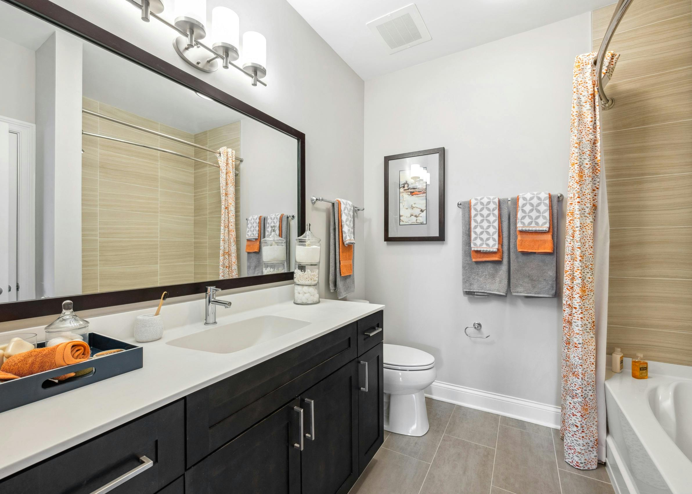 Interior view of an AMLI Deerfield bathroom with large mirror, dark wood cabinets, white countertop and garden tub