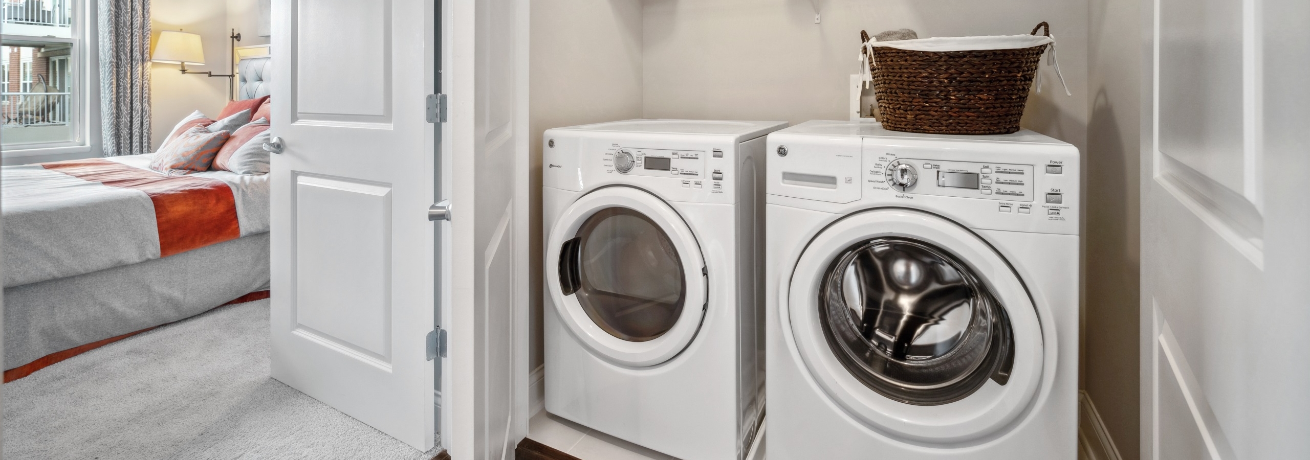 Full size white side by side washer and dryer inside of a closet next to a bedroom at AMLI Deerfield apartments.
