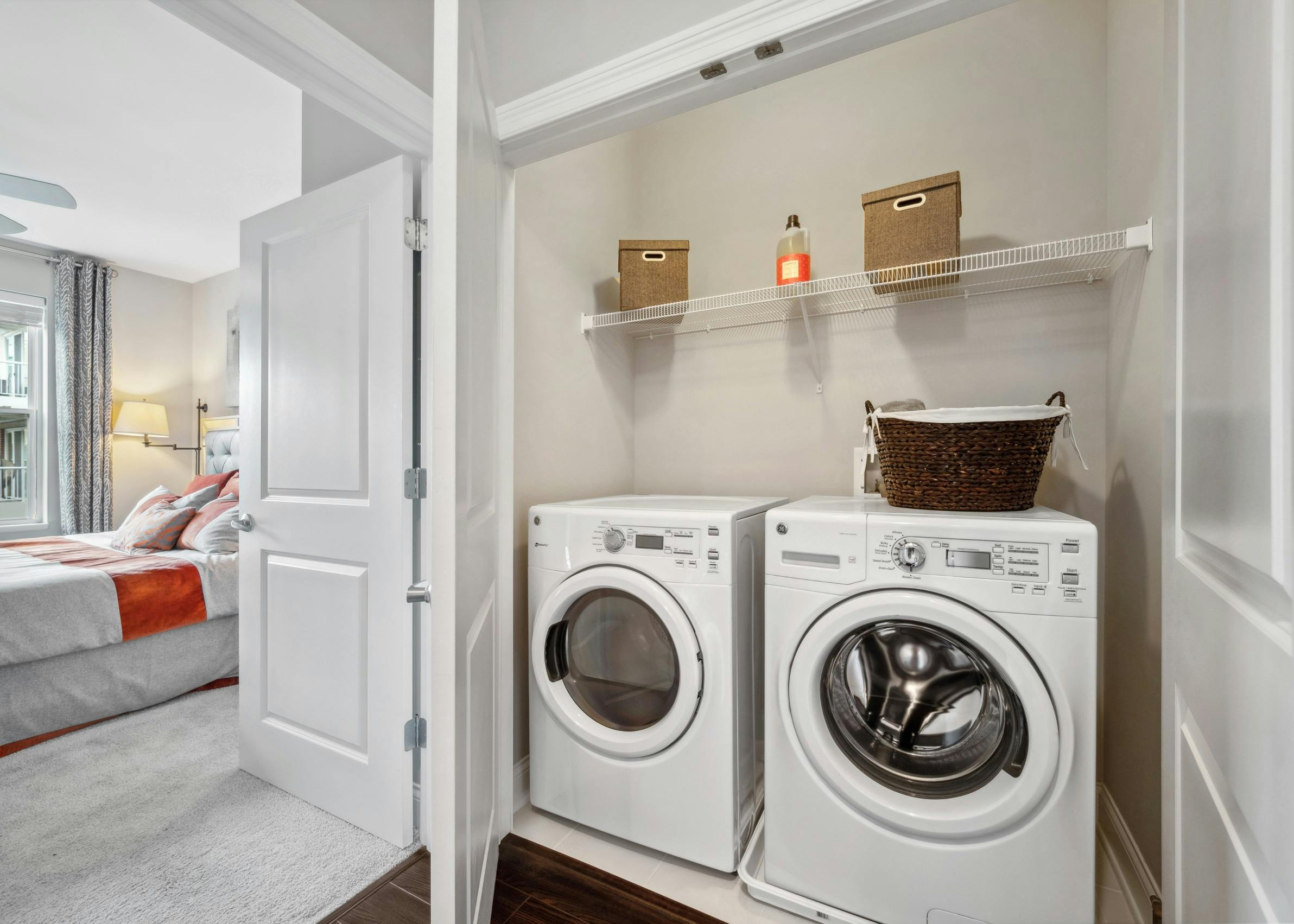 Full size white side by side washer and dryer inside of a closet next to a bedroom at AMLI Deerfield apartments.