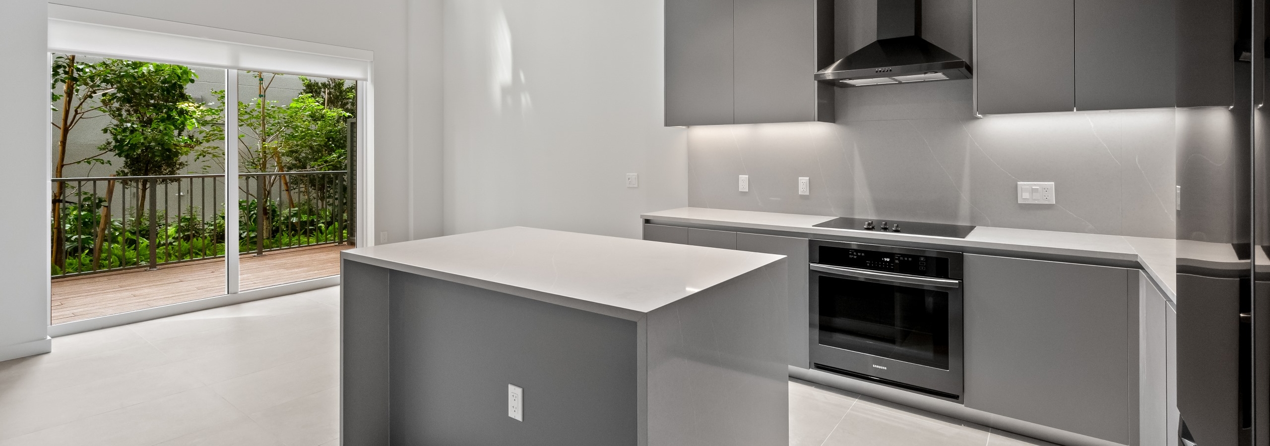 Interior view of modern kitchen and two-story living space with large windows and private patio at AMLI Wynwood apartments.