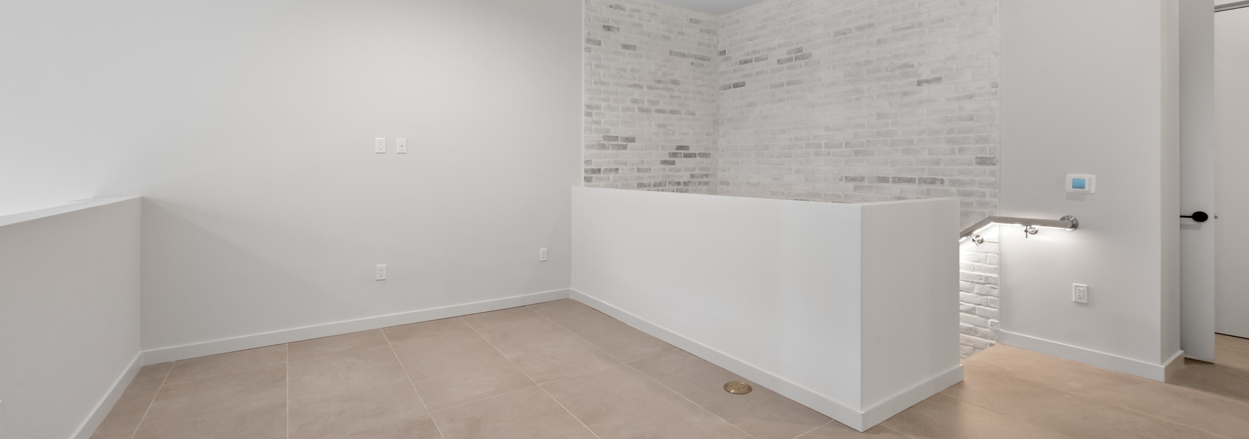 AMLI Wynwood open apartment living or working loft space with tan porcelain tiled flooring and white brick accent wall.