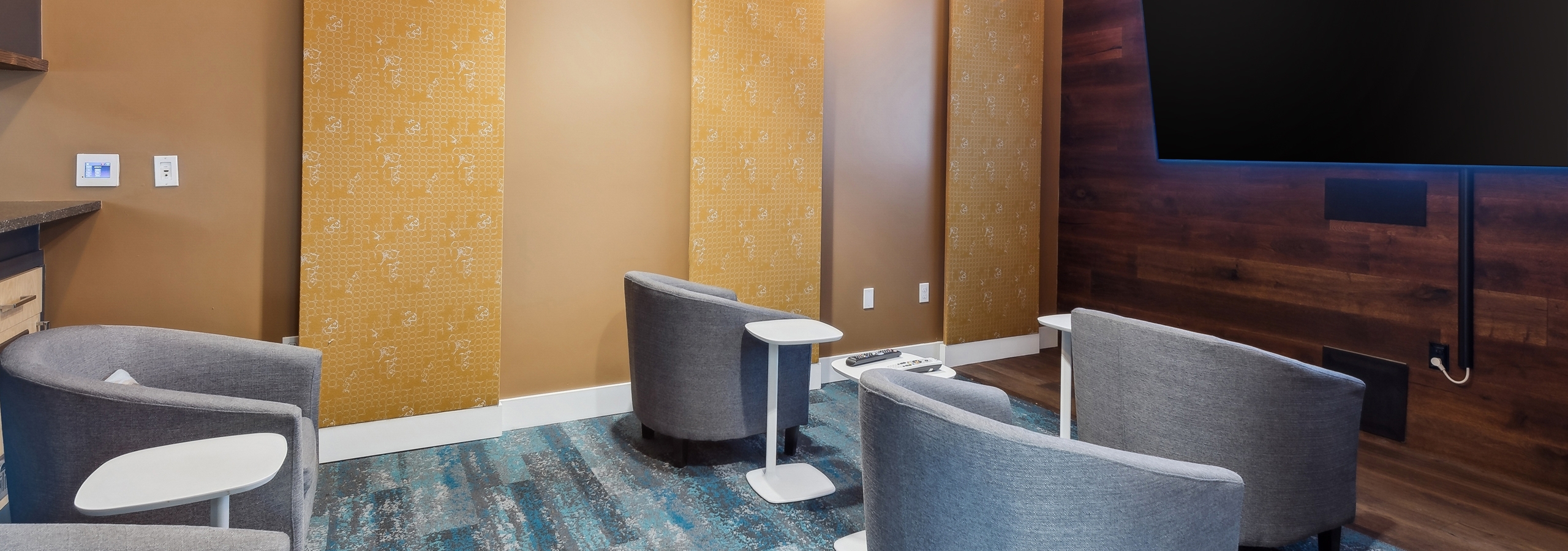 AMLI South Lake Union apartments resident movie theater with a large wall mounted TV and lounge chairs with side tables.