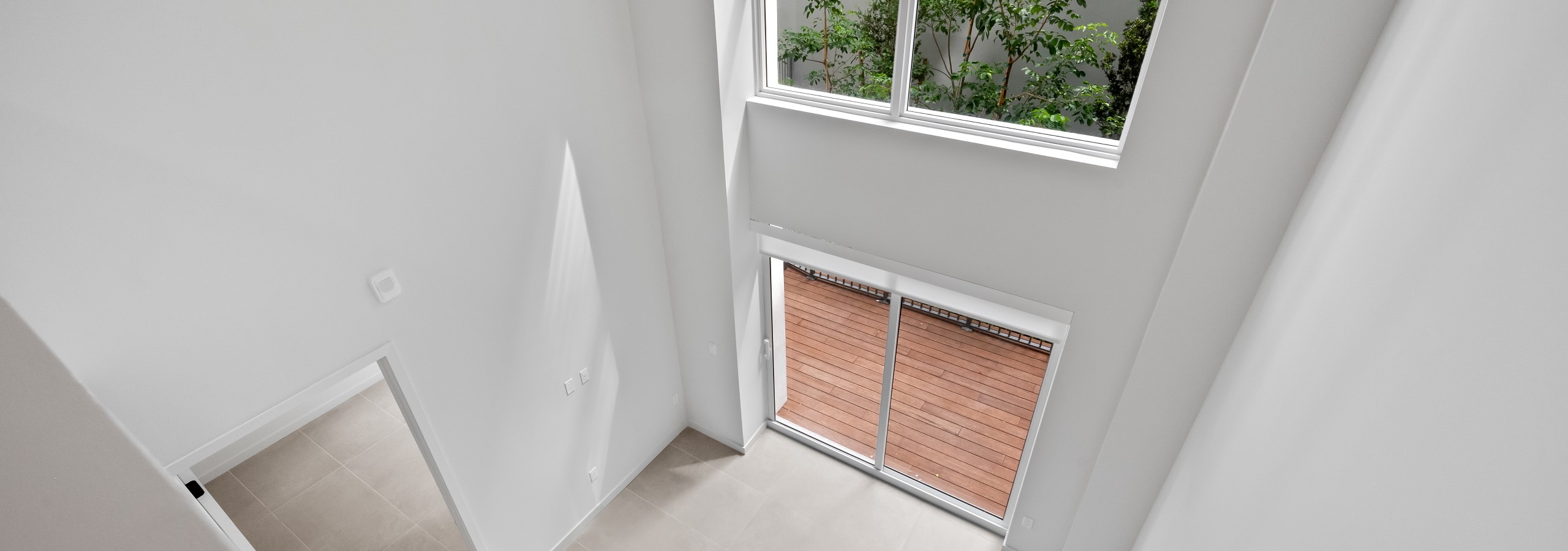 Overhead view of two story loft living area with large windows above sliding doors leading to private patio at AMLI Wynwood apartments.