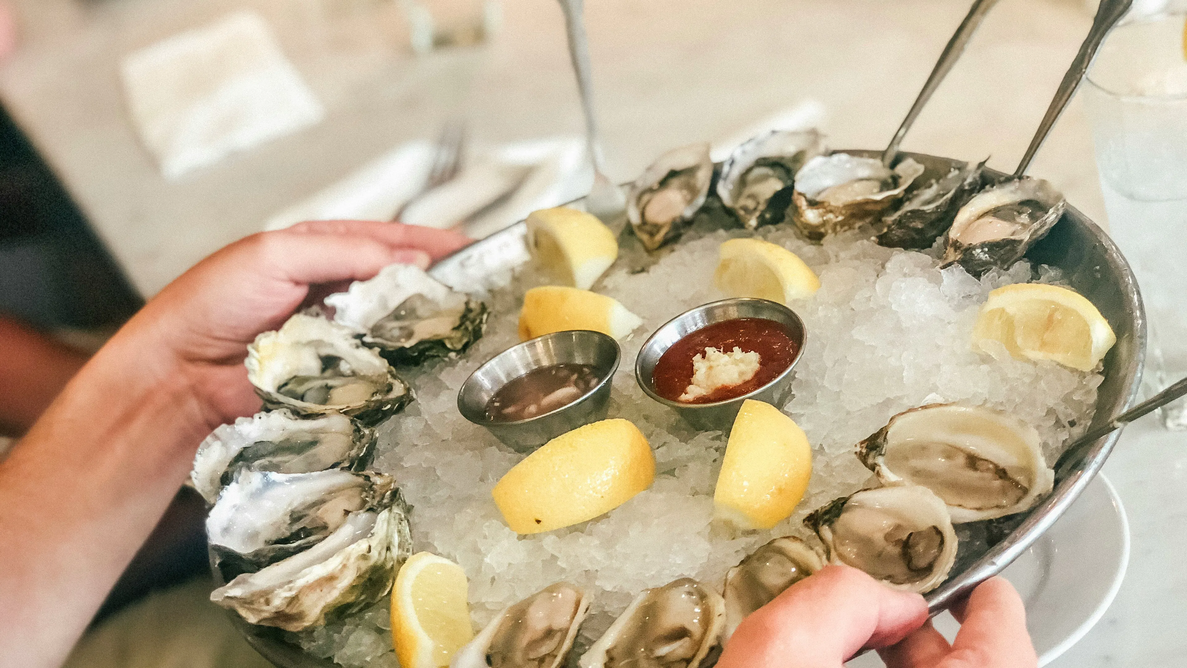 A tray of oysters on ice garnished with lemon and tartar sauce