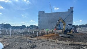 Daytime view of AMLI Treehouse construction site with big concrete wall and digger and construction workers
