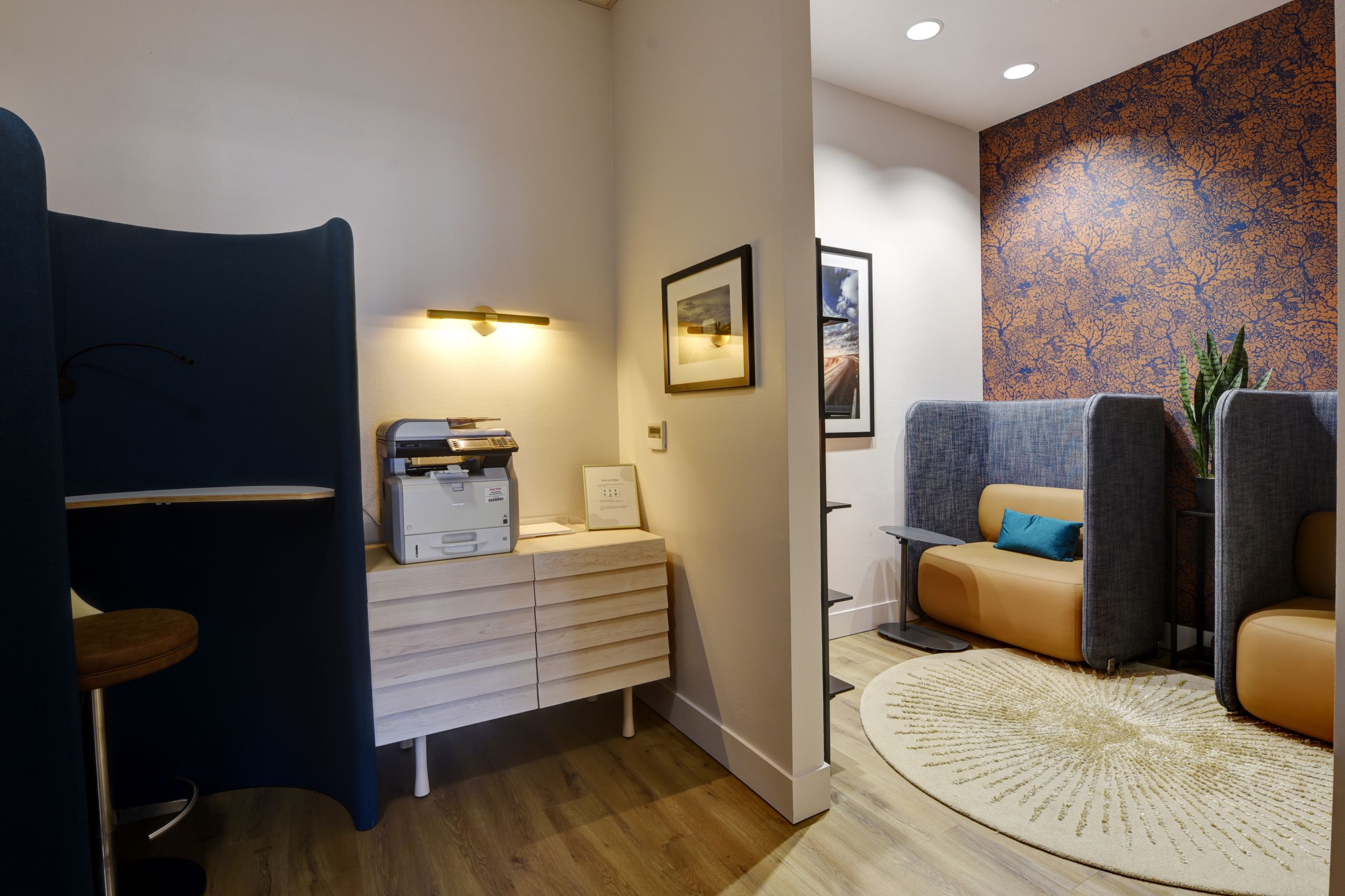 Workstation at AMLI South Lake Union apartments with printer, framed artwork, and cozy seating alcoves featuring blue and tan booths.