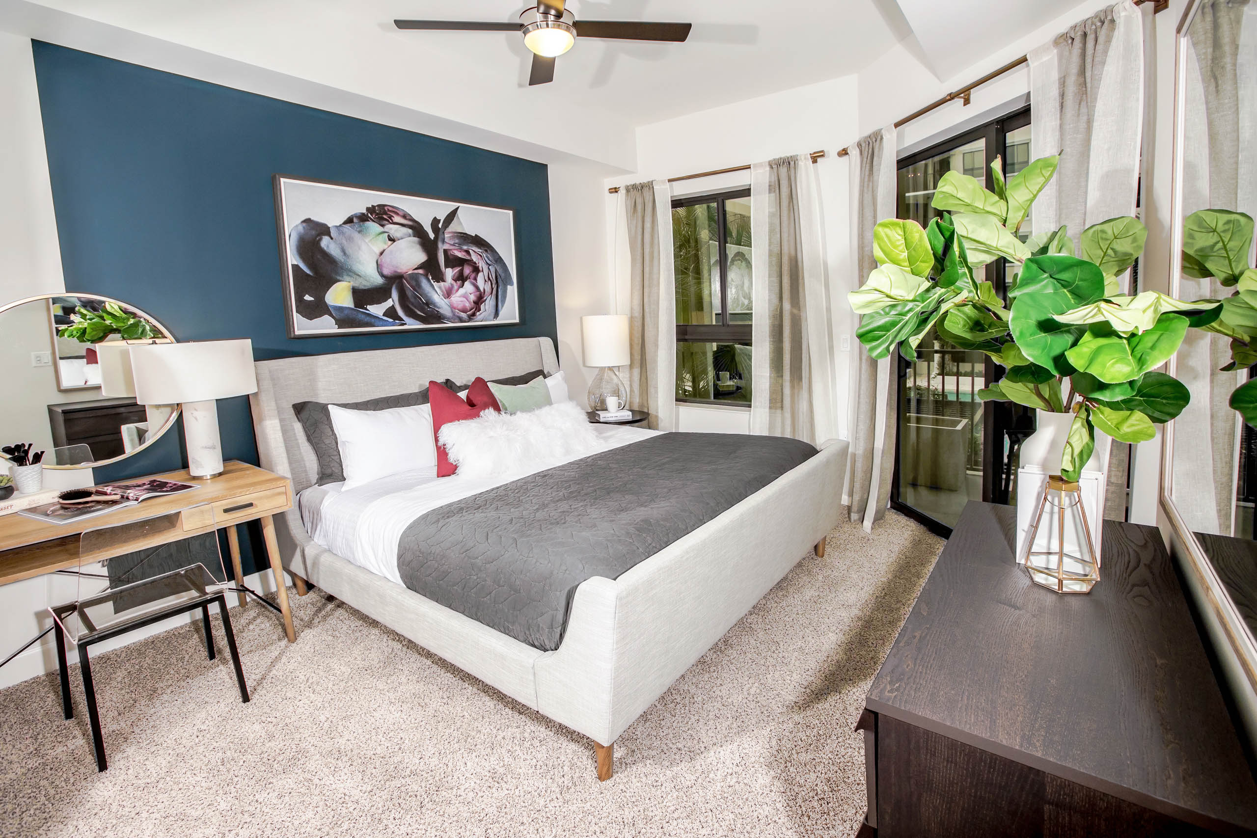 Interior view of an AMLI Joya apartment bedroom with a bed underneath black and white wall art and open window to a sky view.