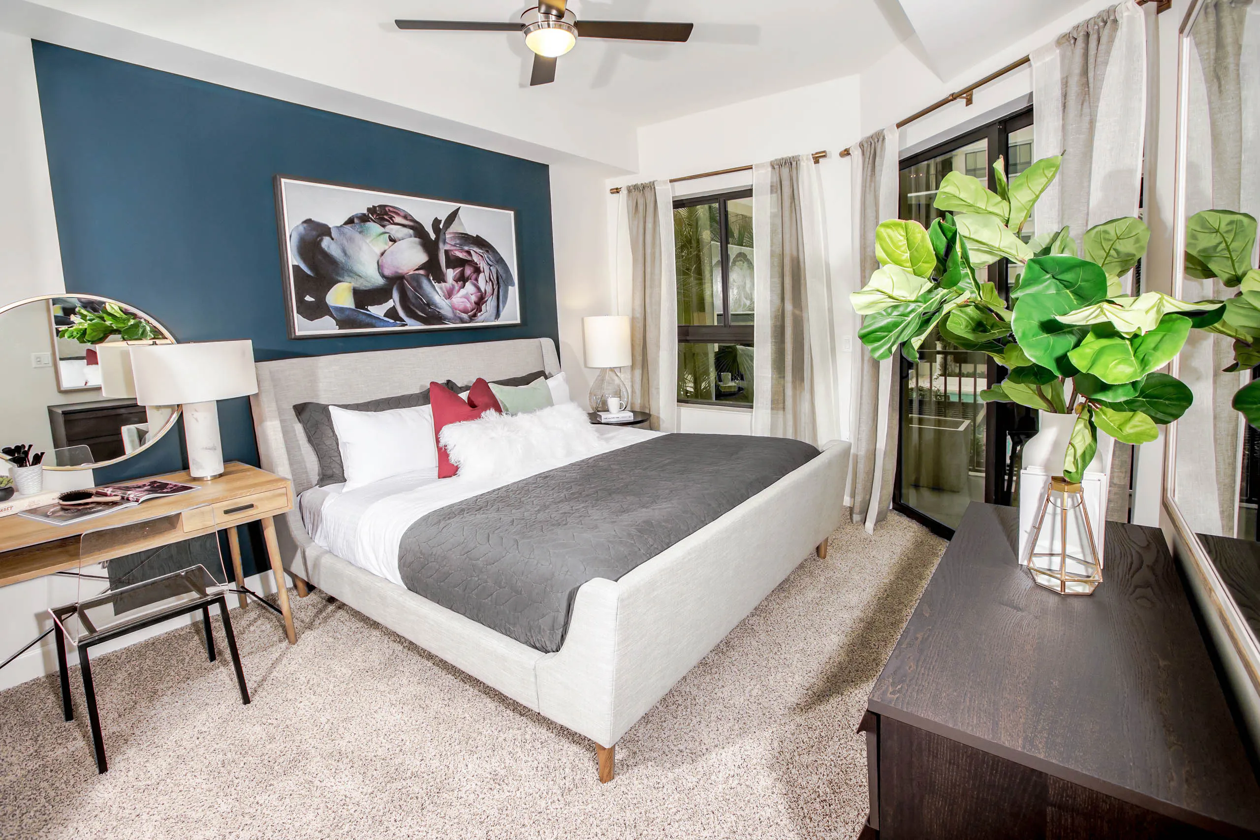 Interior view of an AMLI Joya apartment bedroom with a bed underneath black and white wall art and open window to a sky view.