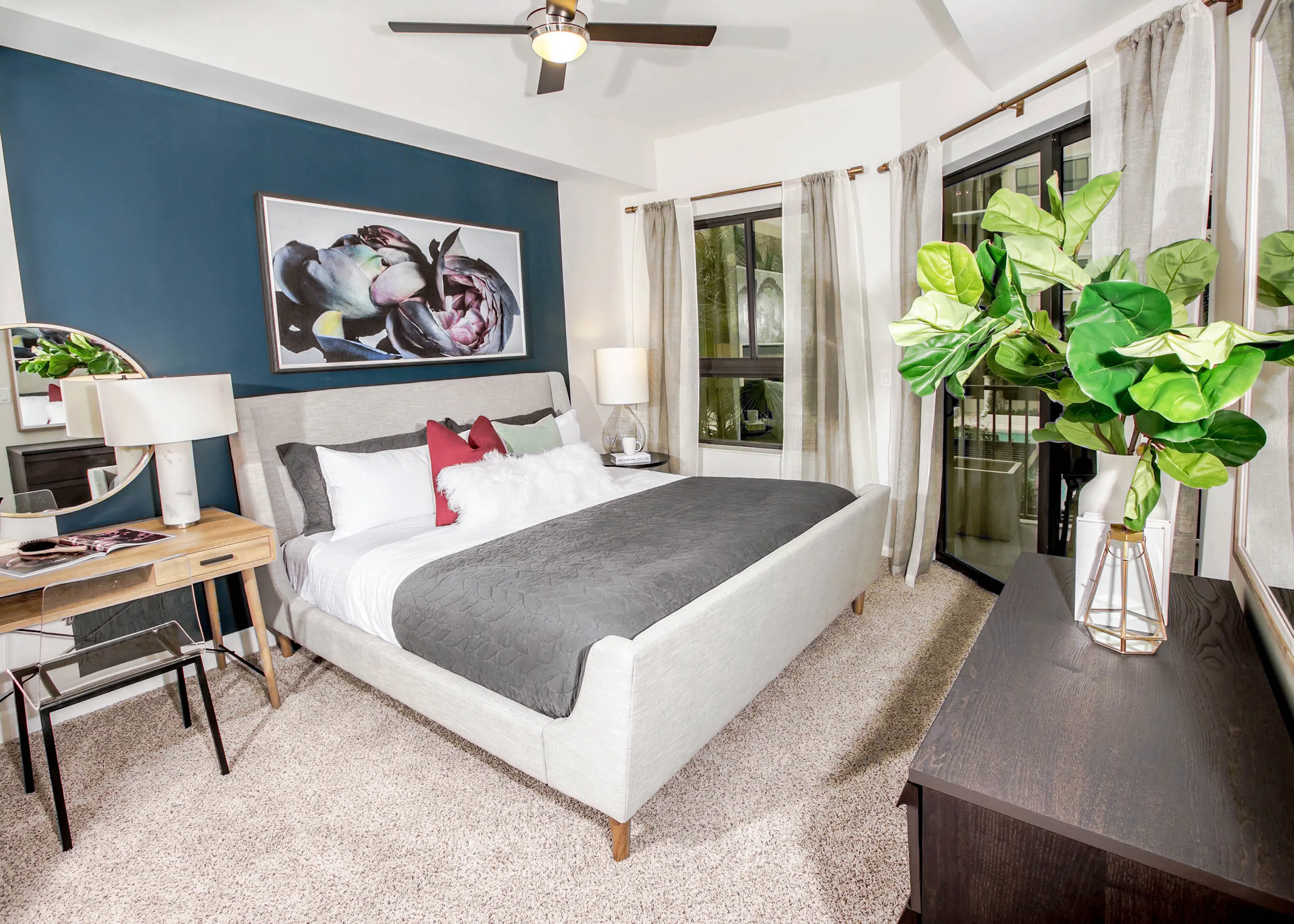 Interior view of an AMLI Joya apartment bedroom with a bed underneath black and white wall art and open window to a sky view.