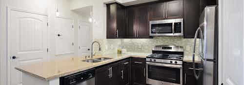 Interior of AMLI Spanish HIlls apartment kitchen with dark cabinetry, granite countertops and stainless steel appliances