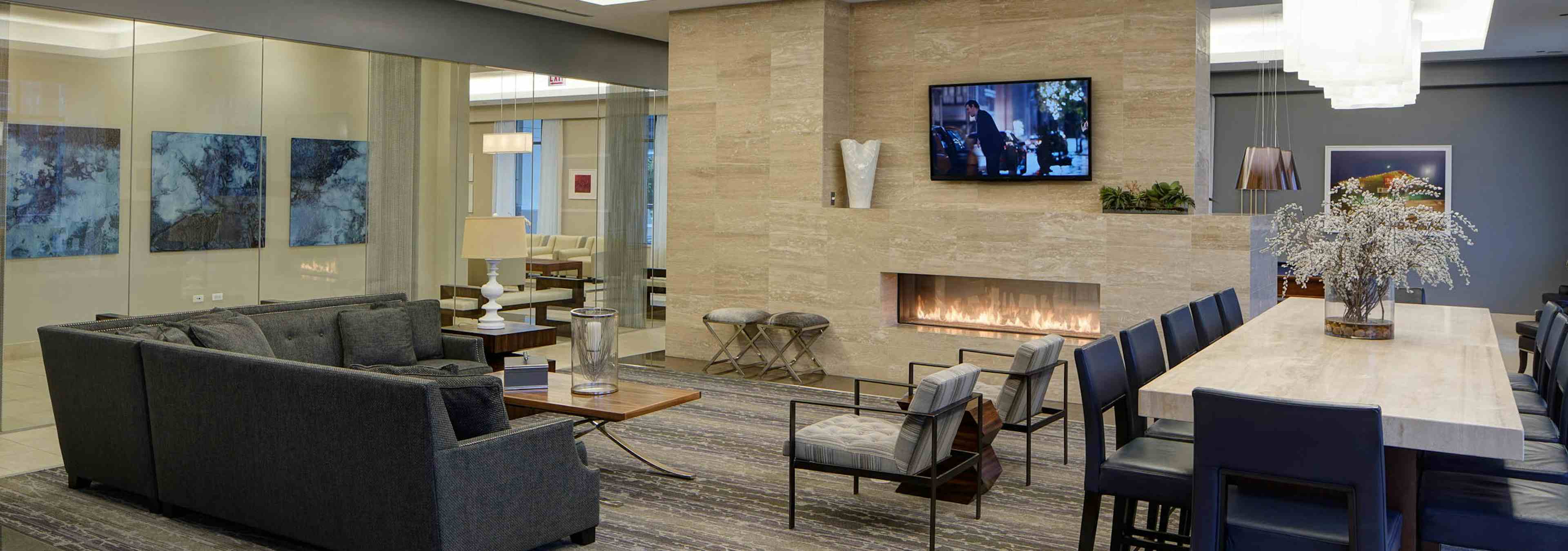 Interior view of AMLI River North clubroom with a large fireplace and an L shaped couch and a high rise table with barstools