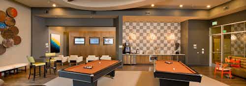 Interior view of AMLI RidgeGate game lounge with checkered backsplash, java bar and two billiards tables and gaming stations