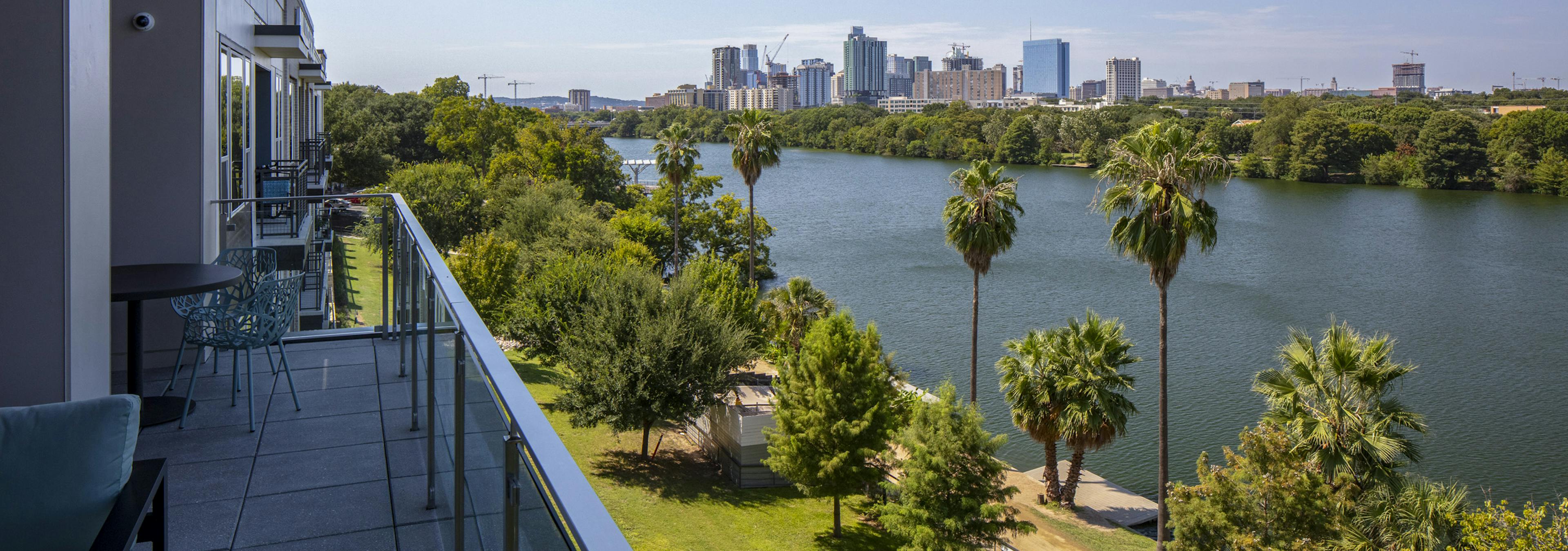 Daytime view of downtown Austin skyline and Lady Bird Lake from AMLI South Shore apartment building balcony with blue chairs 