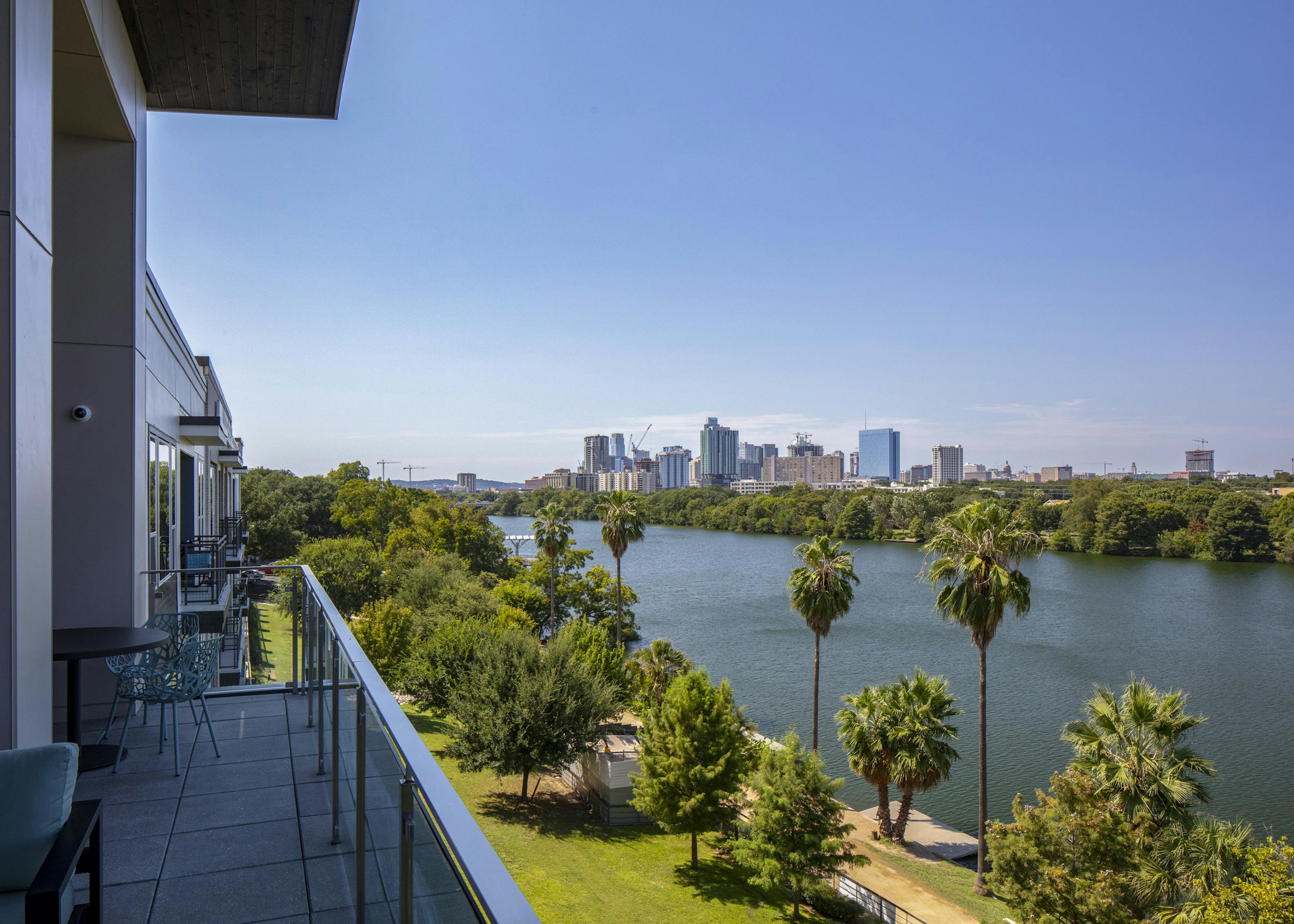 Daytime view of downtown Austin skyline and Lady Bird Lake from AMLI South Shore apartment building balcony with blue chairs 