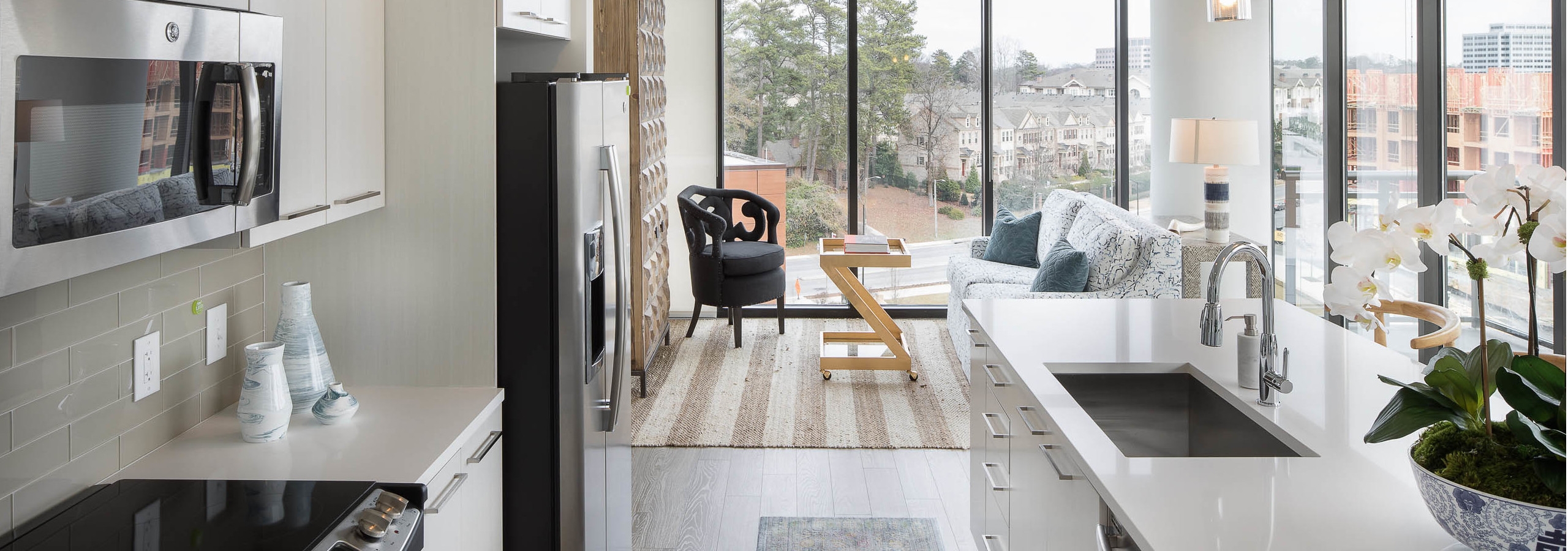AMLI 3464 kitchen with white cabinets and countertops paired with beige backsplash and surrounding floor to ceiling windows