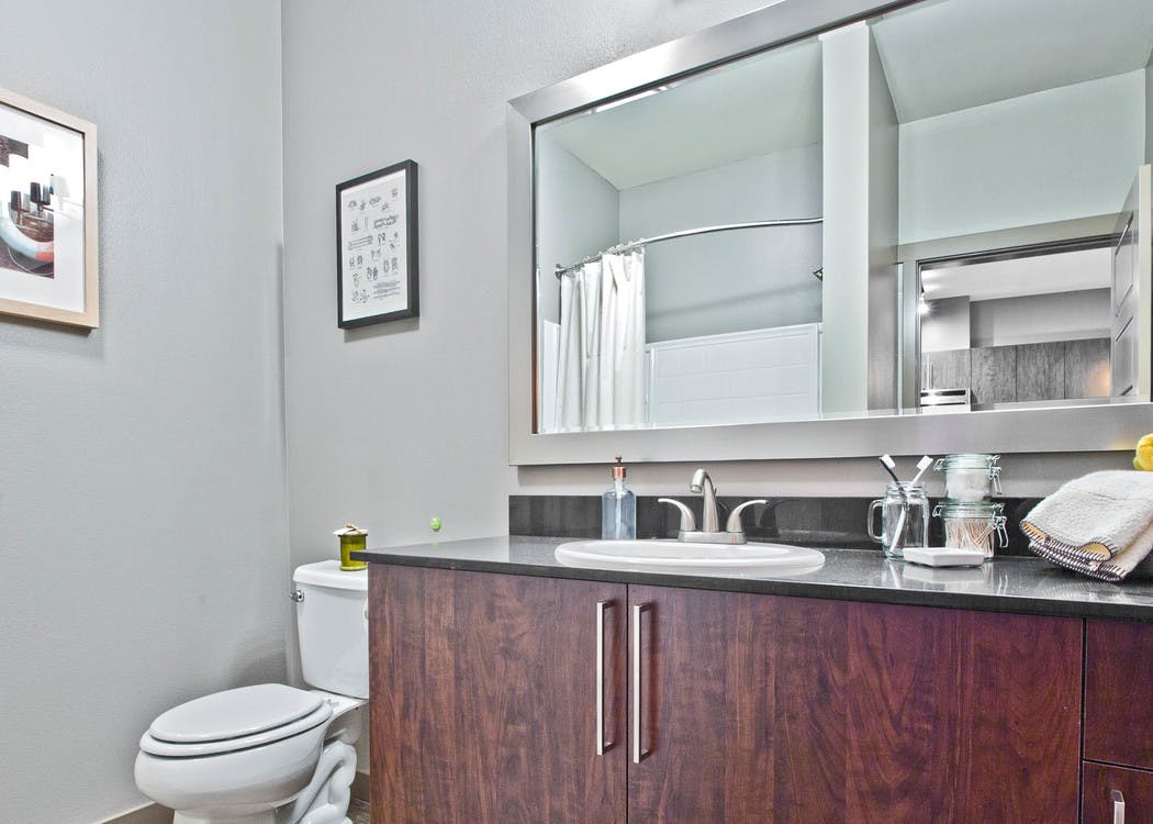 Interior view of an AMLI Mark24 apartment bathroom with grey walls and lots of dark cabinet storage