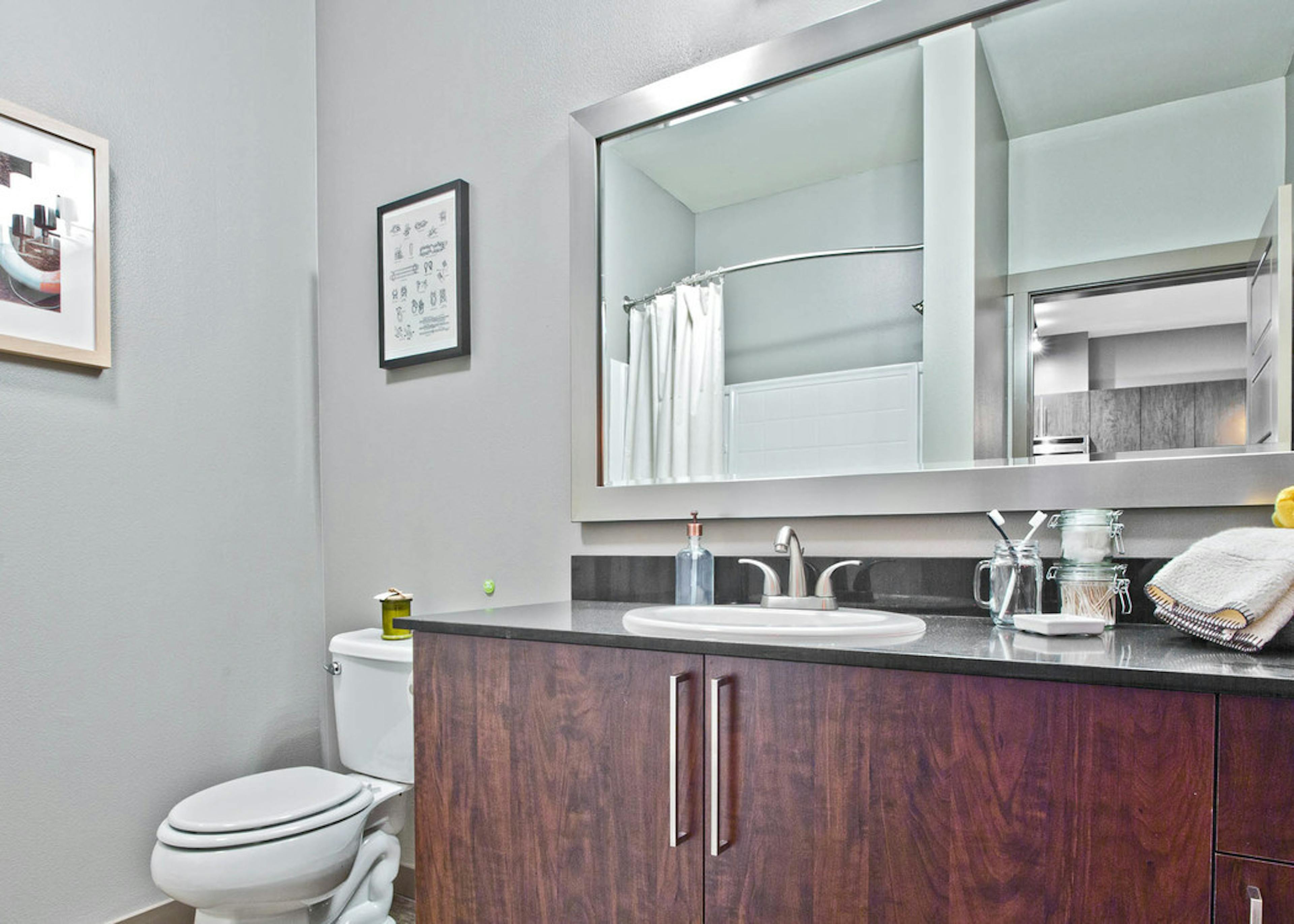 Interior view of an AMLI Mark24 apartment bathroom with grey walls and lots of dark cabinet storage 