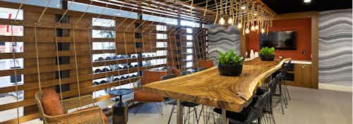 Interior of AMLI Marina Del Rey apartment workout rest area with live edge wood slab table and bulb rope pendant lighting