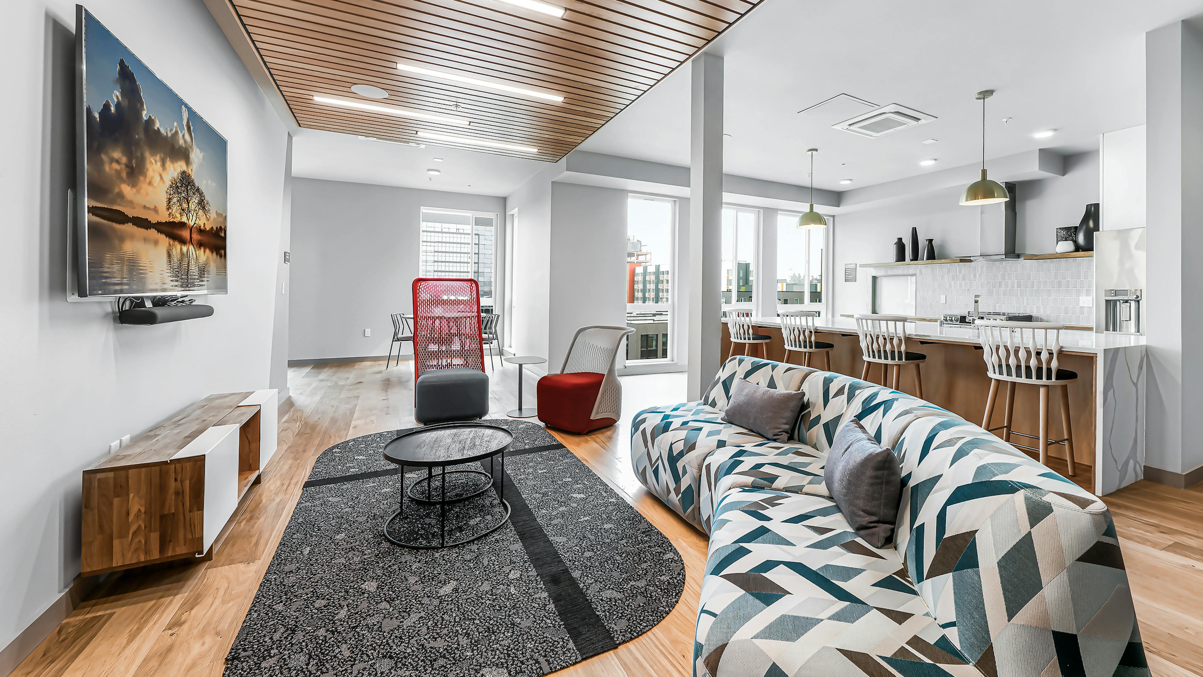 Interior of AMLI Spring District clubroom with wood floors and colorful sofa with TV on wall and additional seating areas