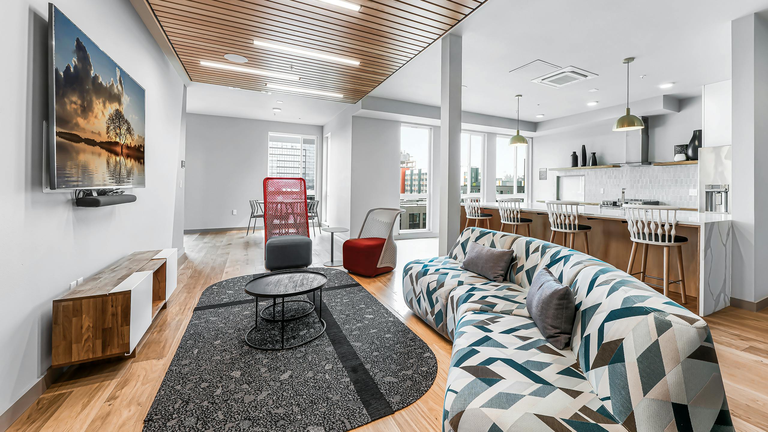 Interior of AMLI Spring District clubroom with wood floors and colorful sofa with TV on wall and additional seating areas