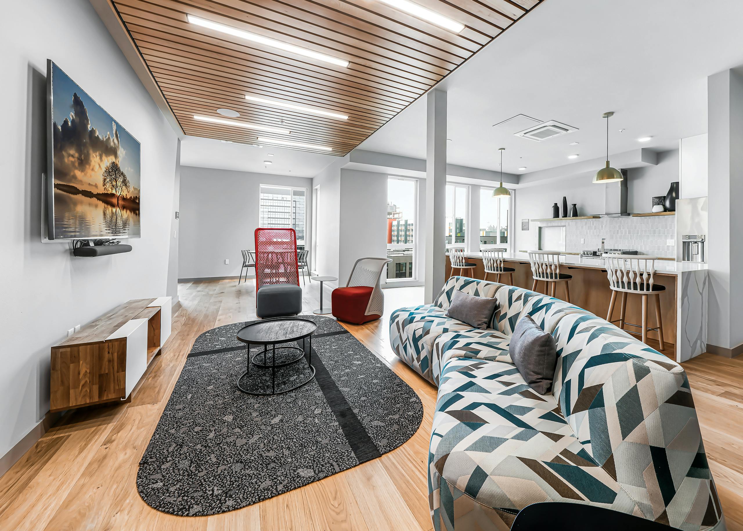 Interior of AMLI Spring District clubroom with wood floors and colorful sofa with TV on wall and additional seating areas