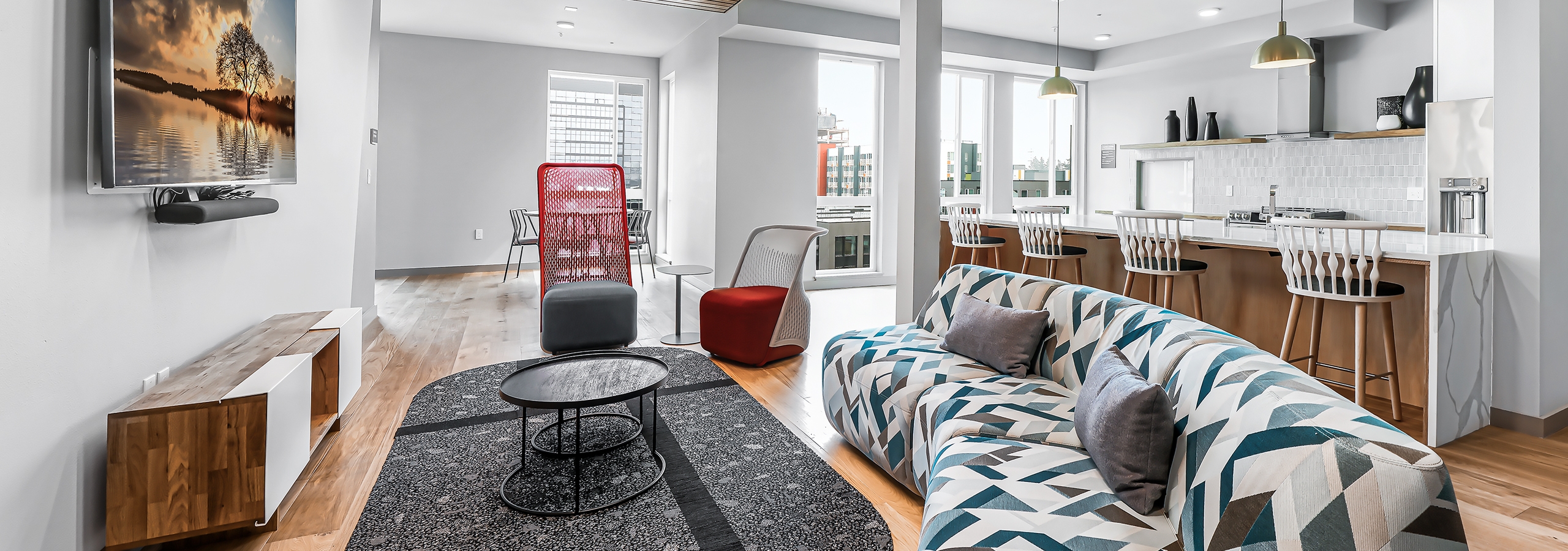Interior of AMLI Spring District clubroom with wood floors and colorful sofa with TV on wall and additional seating areas